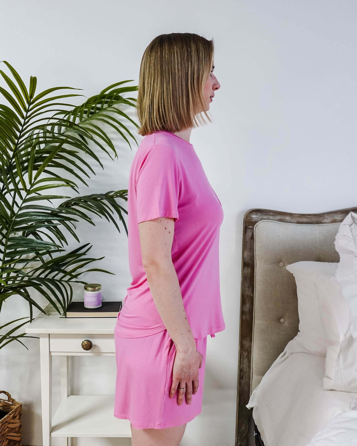 Bubblegum Pink Tee Short Bamboo Pajama Set worn by a woman standing in profile in a cozy bedroom.
