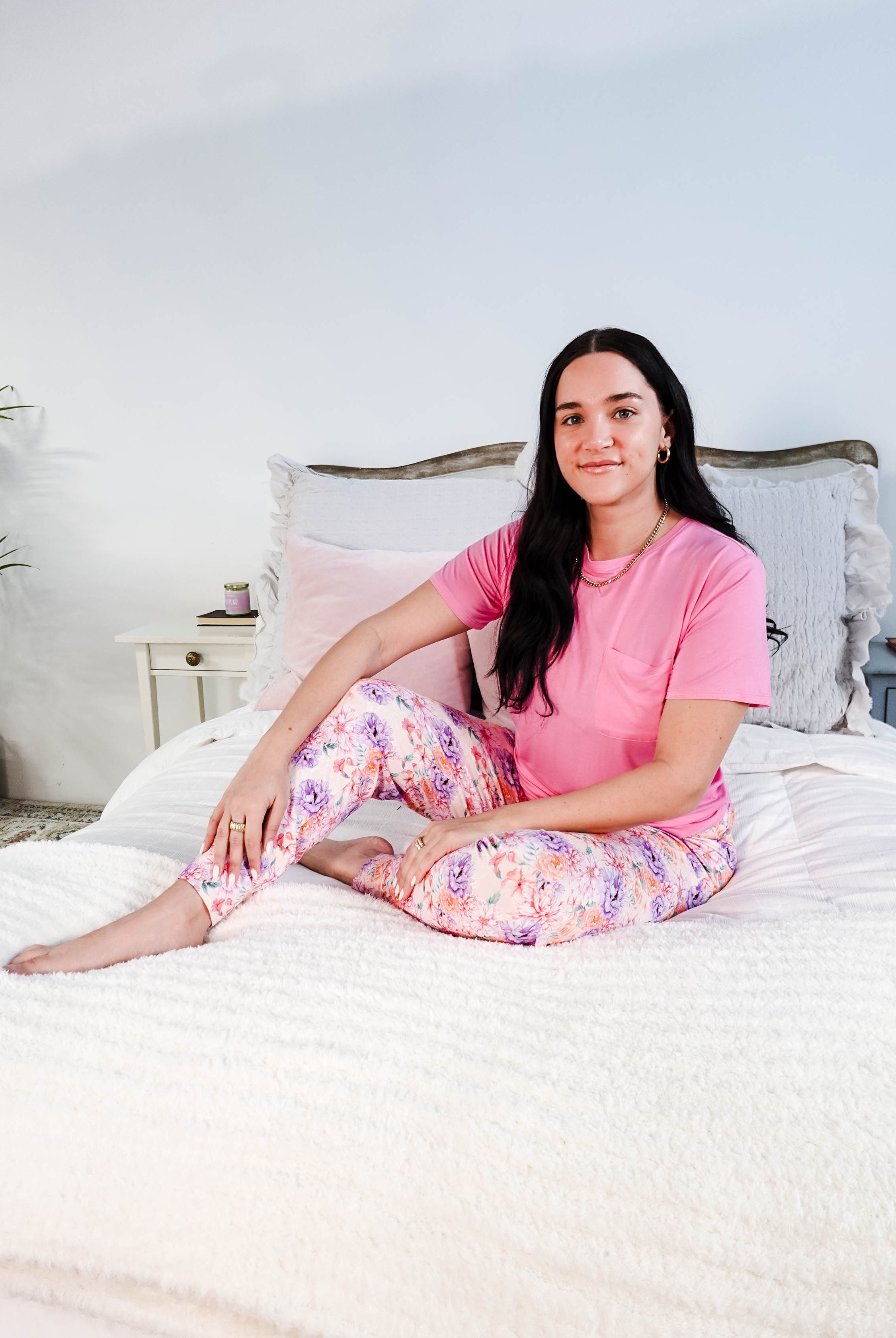 Model wearing the Dream In Blooms Tee & Jogger Bamboo Lounge Set on a bed with floral joggers.