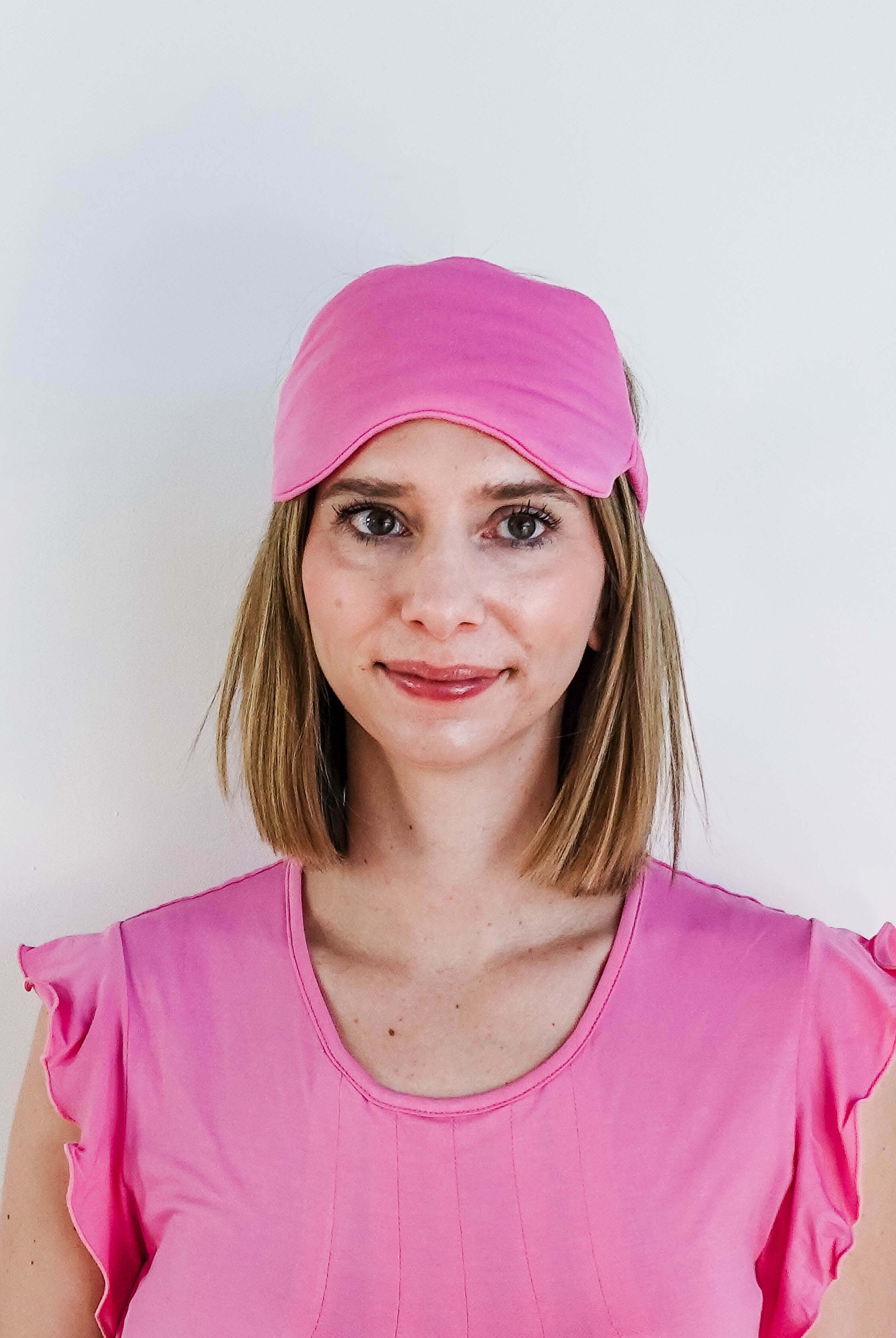 Bubblegum Pink Bamboo Sleep Eye Mask worn by a woman in pink top for comfortable sleep.