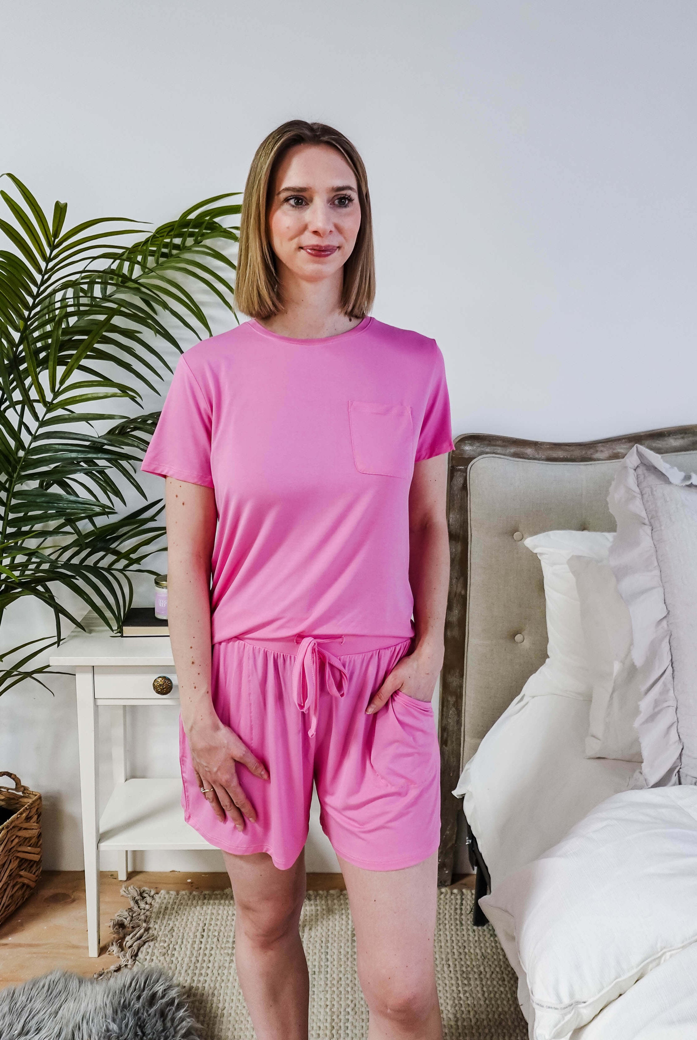 Woman wearing Bubblegum Pink Tee Short Bamboo Pajama Set, relaxed at home with a cozy bedroom background.