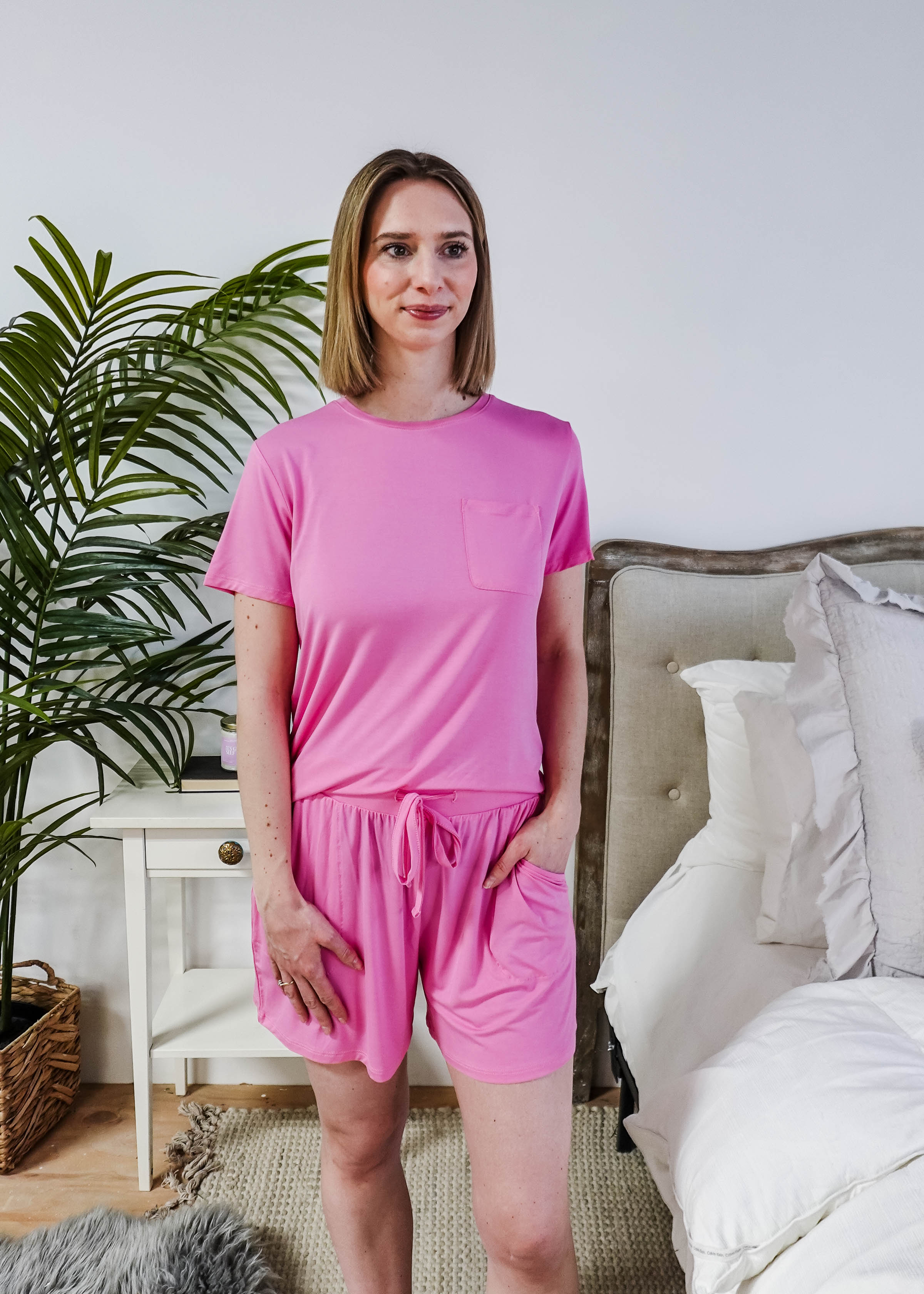 Woman wearing Bubblegum Pink Tee Short Bamboo Pajama Set, relaxed at home with a cozy bedroom background.