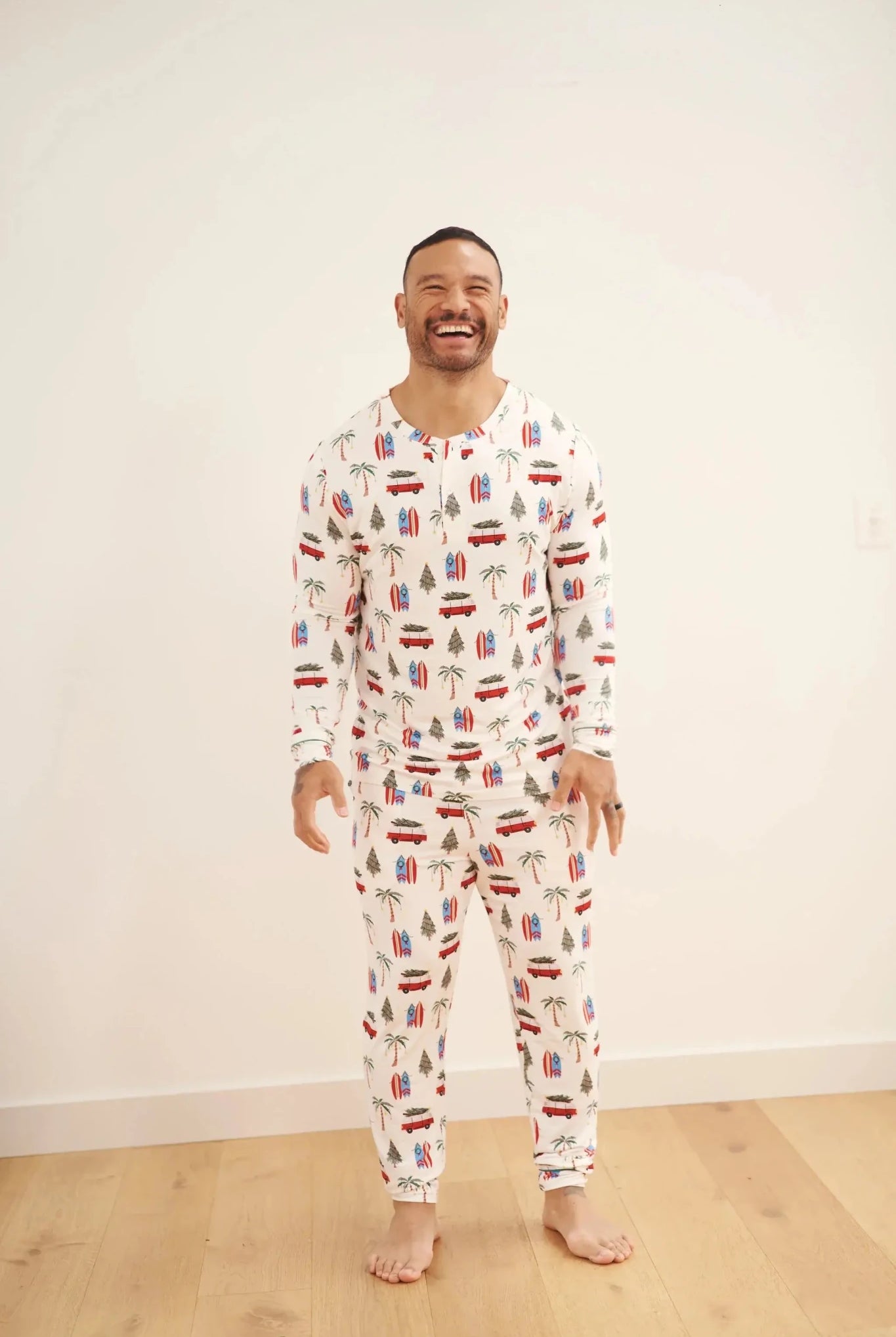 Smiling man wearing Cali Beachy Christmas Men's Bamboo Henley Jogger Set with tropical designs.