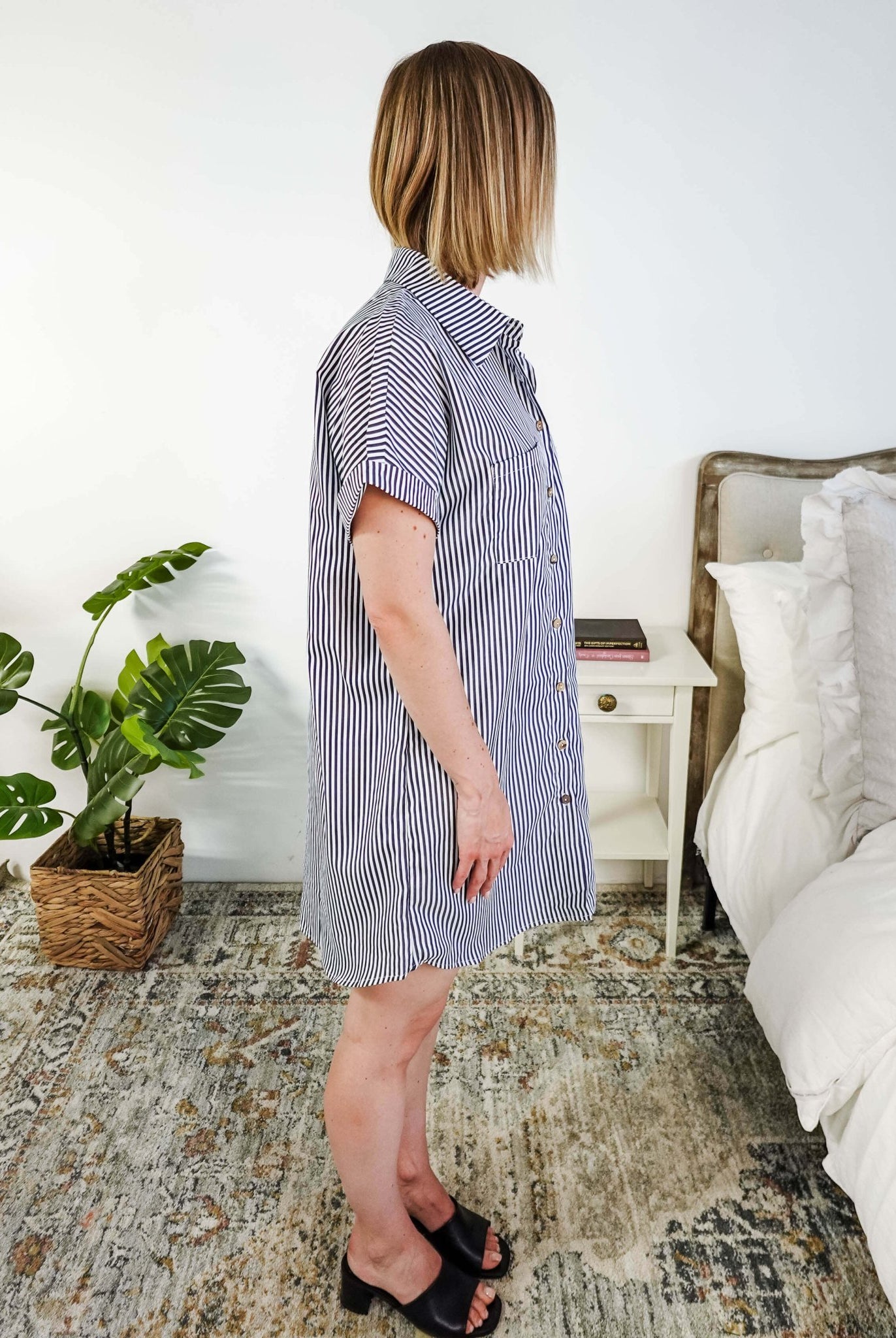 Woman wearing a blue and white striped dress in a bedroom setting. Scarlett Ellie Collared Button-Up Short Sleeve Dress | Cloud Nine Pajamas