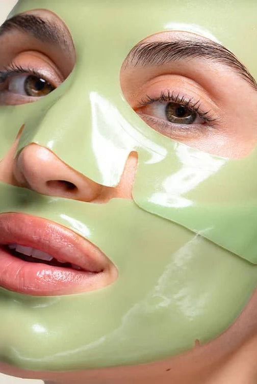 Person wearing a green face mask with a neutral background, Patchology Cool Crush cryo-inspired hydrogel face mask depuffing