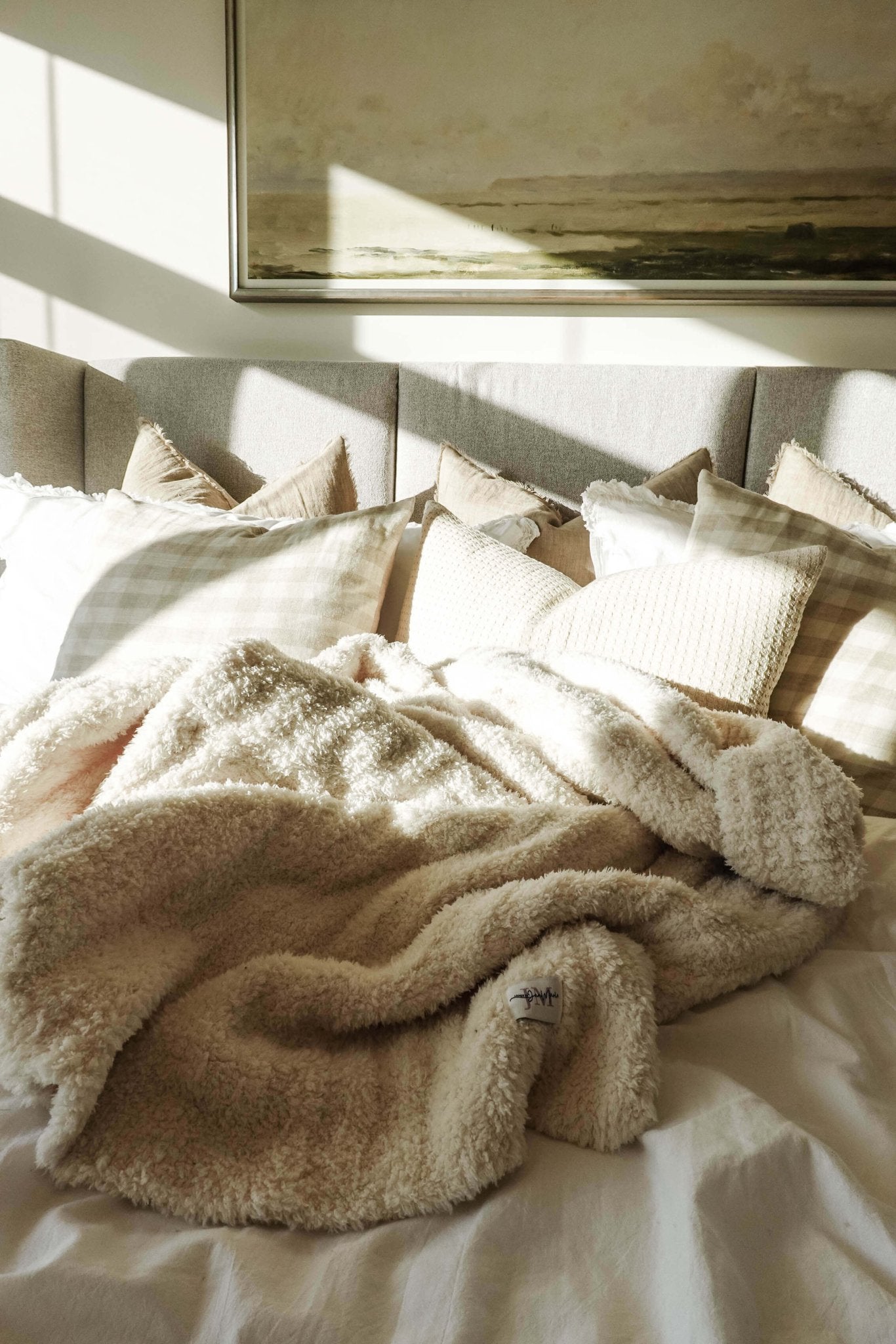 Cozy Cabin Blanket – Oversized Ivory Plush Throw (75″ × 52″) - shown in a beautiful neutral bedroom setting, haphazardly strewn on the bed to show the large size and texture.