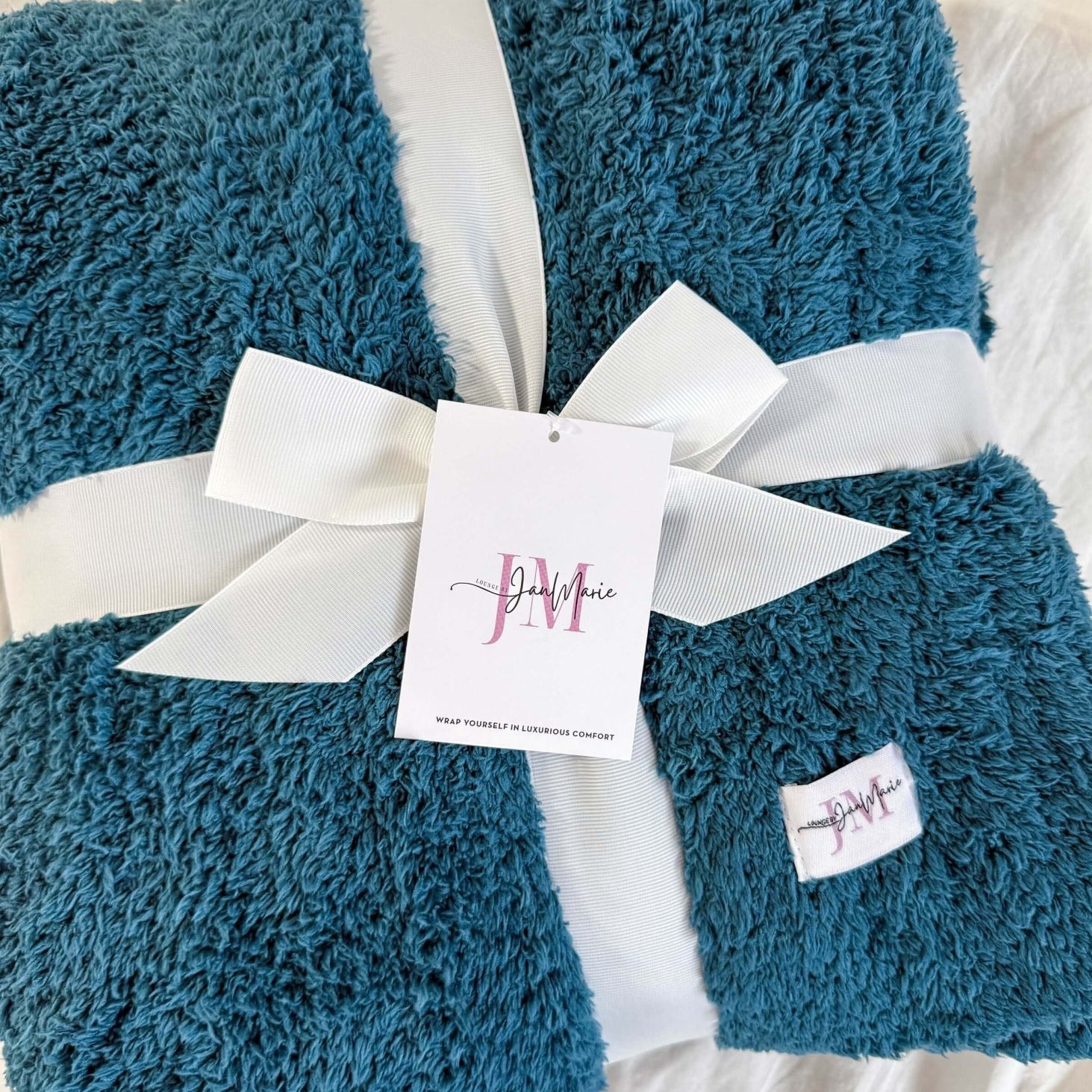 teal blue plush blanket rapped in ribbon on white background