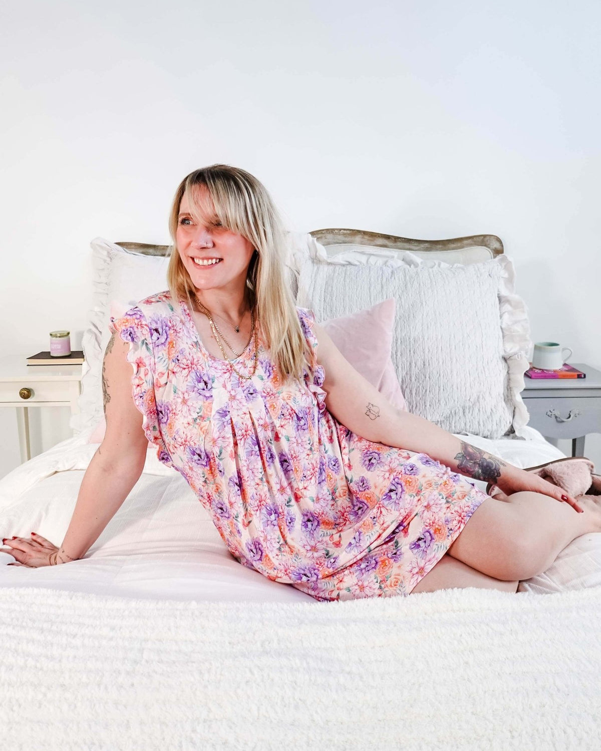 Dream In Blooms Flutter Bamboo Nightgown displayed on a smiling woman sitting on a bed, showcasing romantic sleepwear.