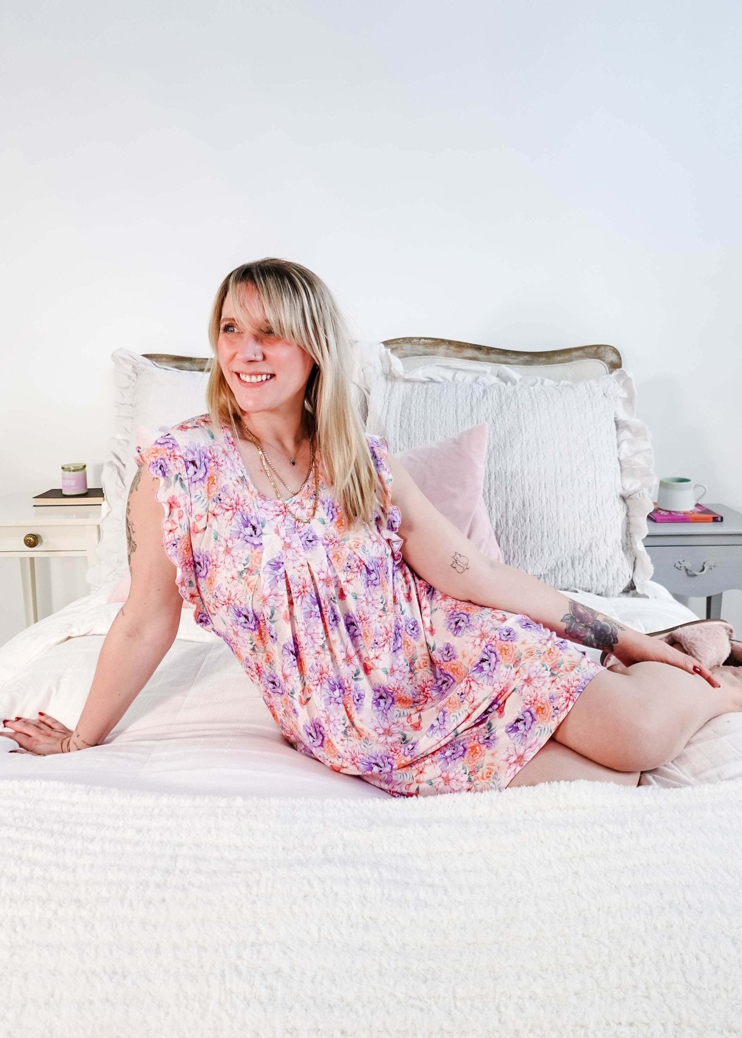 Dream In Blooms Flutter Bamboo Nightgown displayed on a smiling woman sitting on a bed, showcasing romantic sleepwear.