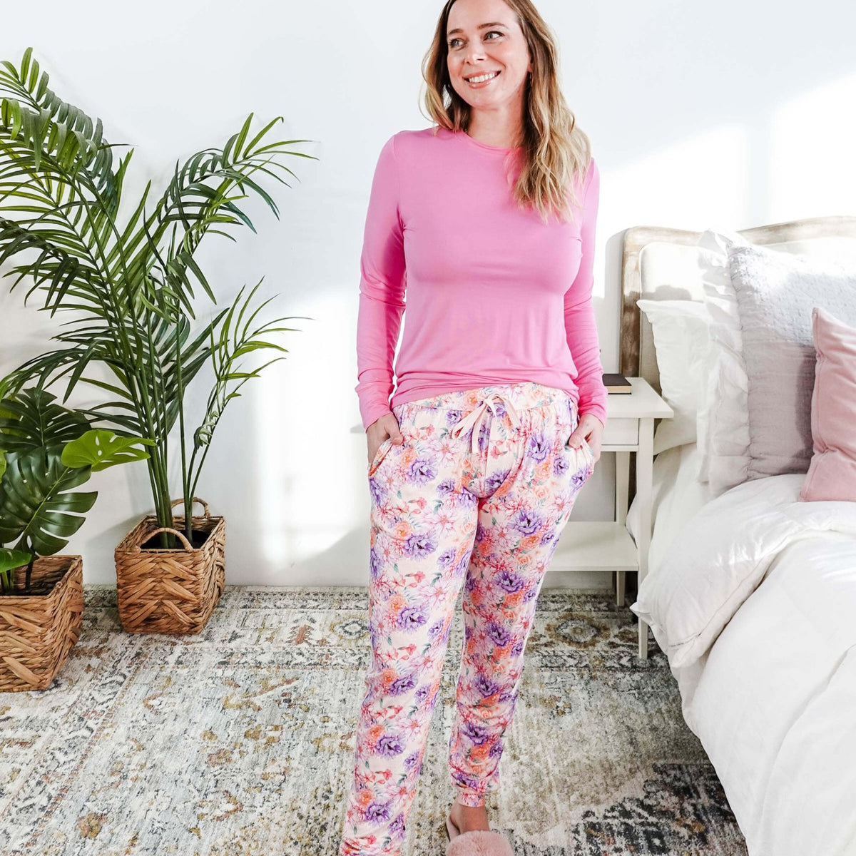 Model wearing the Dream In Blooms Long Sleeve Top & Jogger Bamboo Lounge Set in a cozy bedroom with greenery.