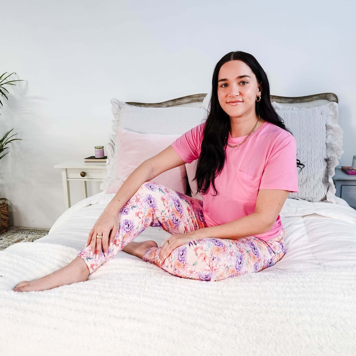 Model wearing the Dream In Blooms Tee & Jogger Bamboo Lounge Set on a bed with floral joggers.