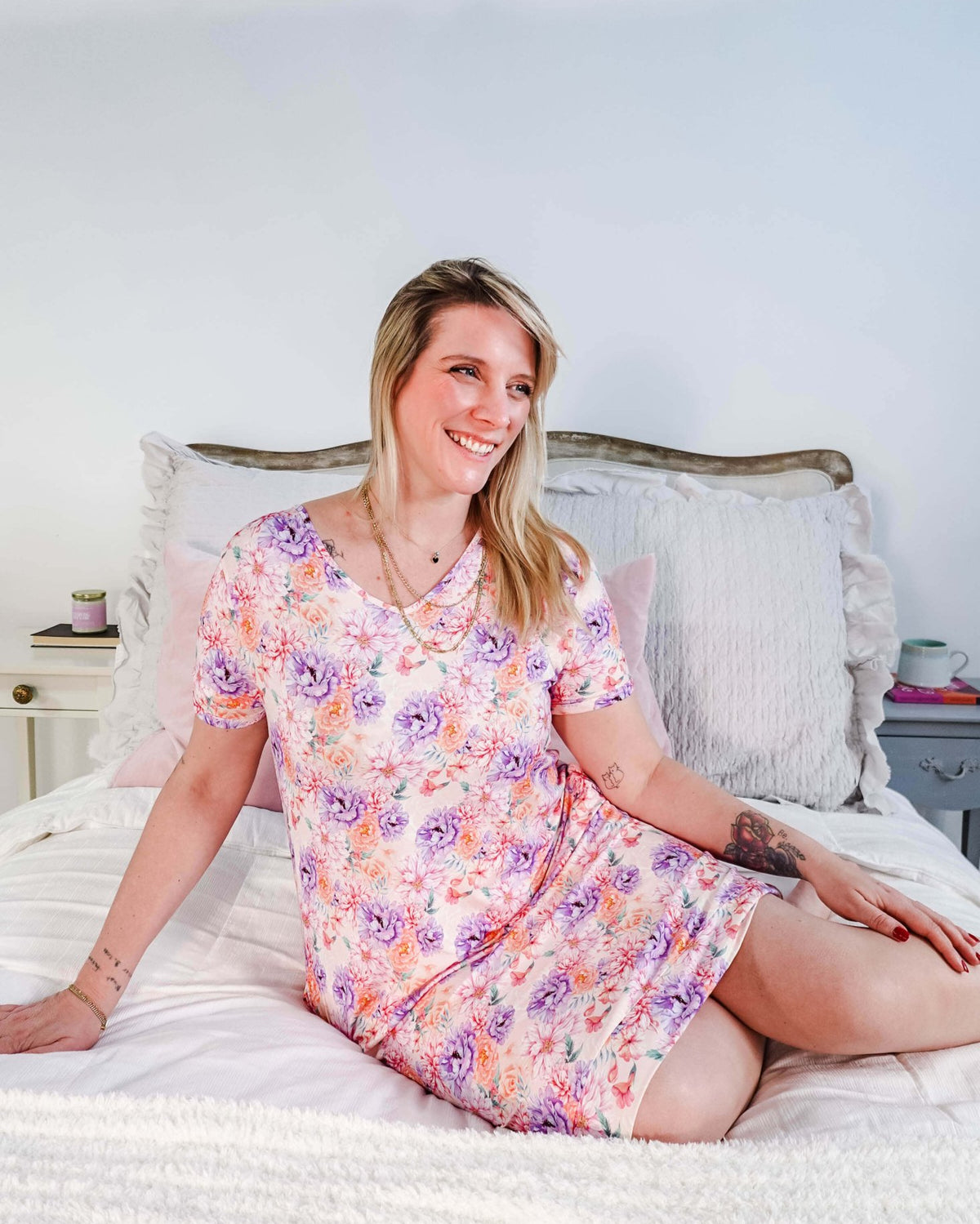 Dream in Blooms V Neck Nightshirt With Pockets worn by a woman sitting on a bed, featuring a floral design.