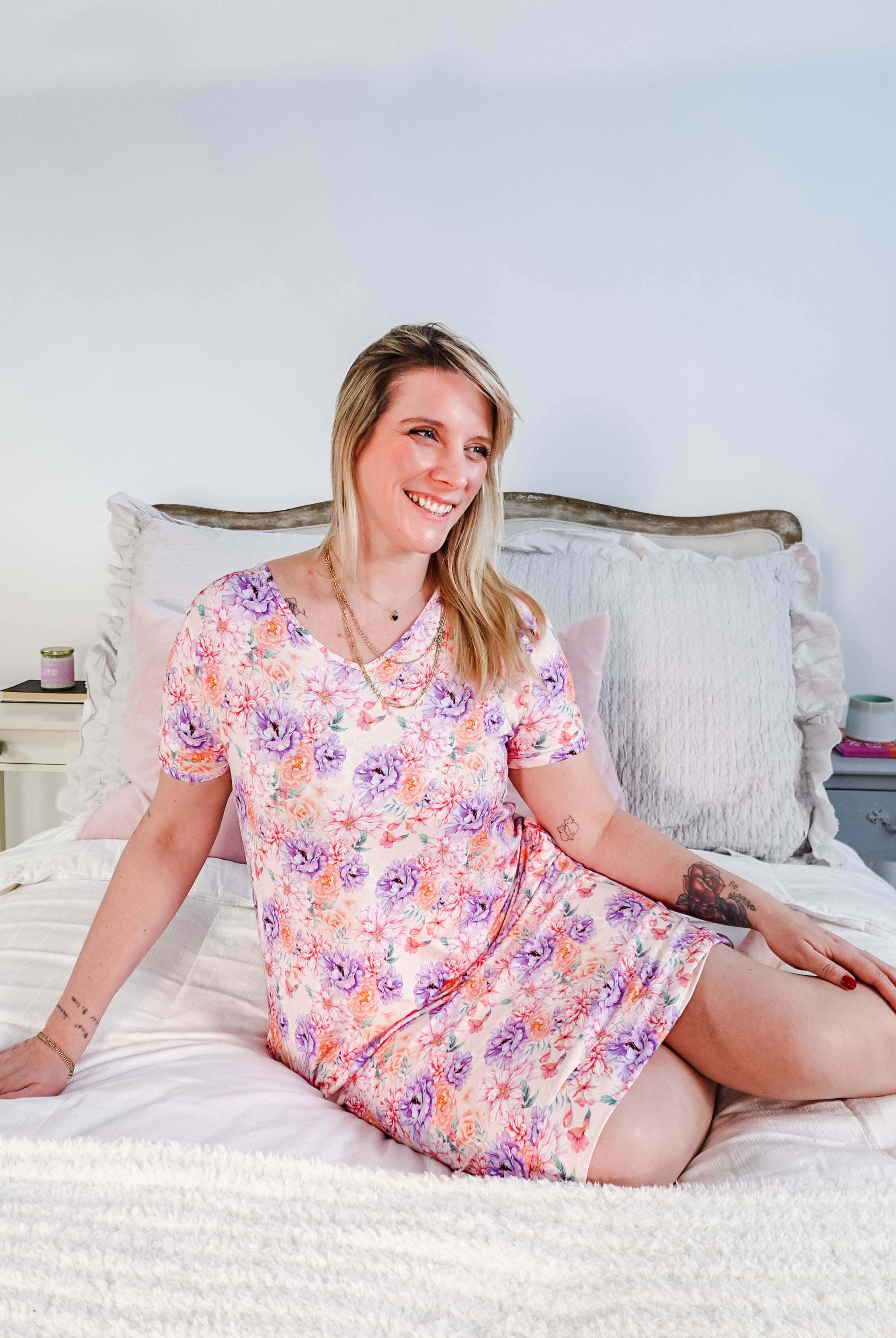Dream in Blooms V Neck Nightshirt With Pockets worn by a woman sitting on a bed, featuring a floral design.