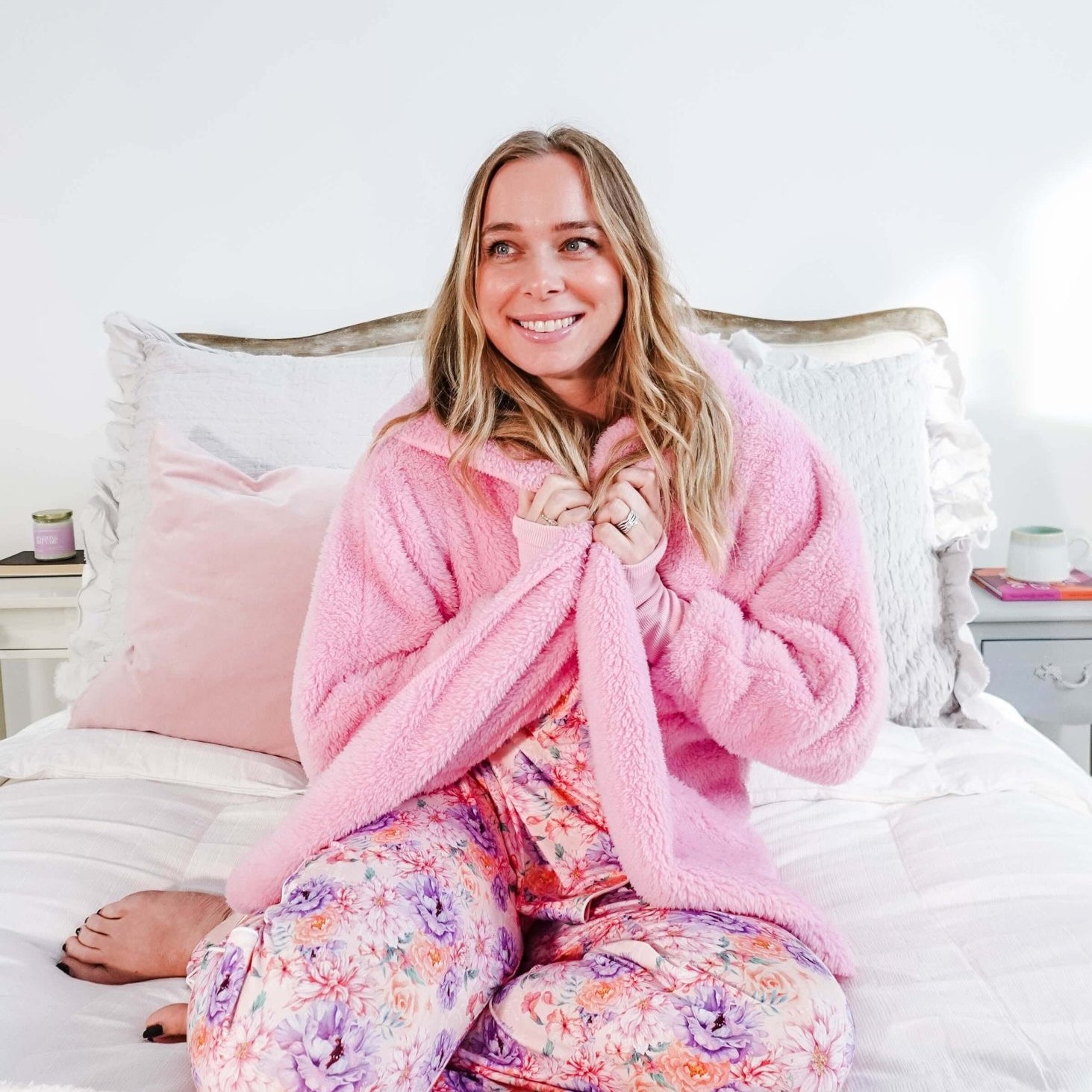 Essential Hooded Fluffy Cozy Cardigan with Pockets worn by a smiling woman sitting on a bed.