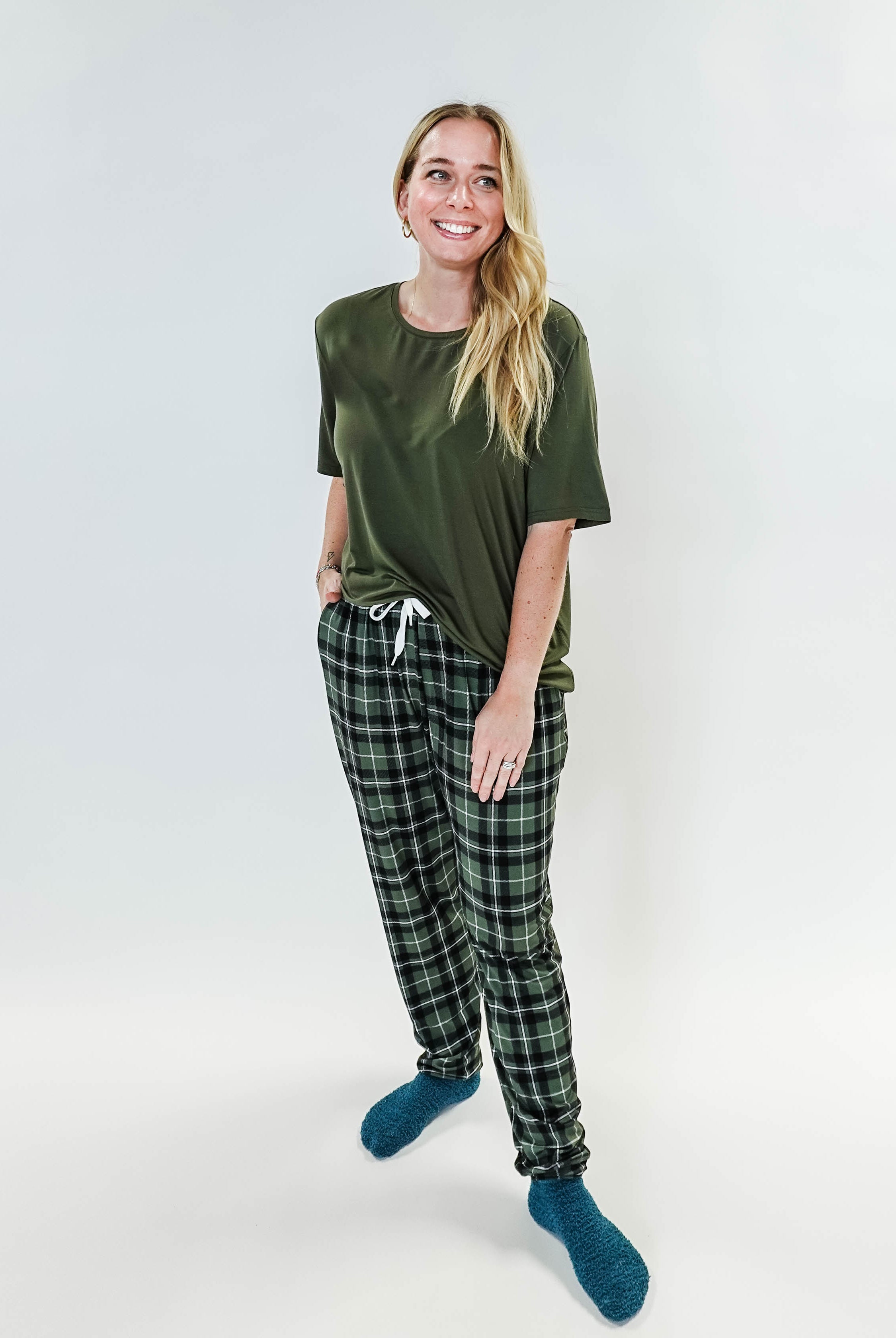 Model wearing Green Plaid Unisex Bamboo Jogger from Bob's Sleepwear Co. with a casual top and cozy socks.