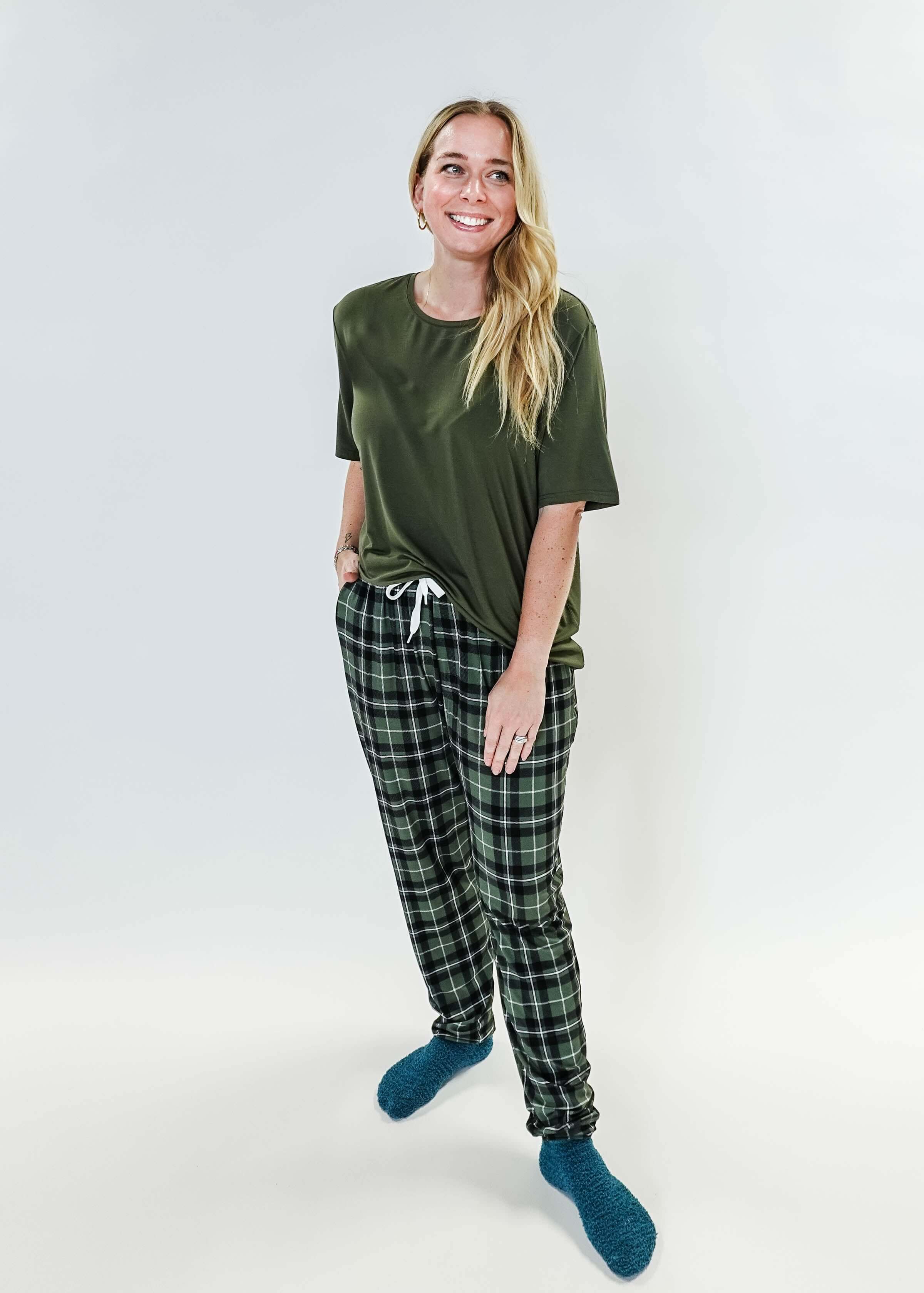 Model wearing Green Plaid Unisex Bamboo Jogger from Bob's Sleepwear Co. with a casual top and cozy socks.