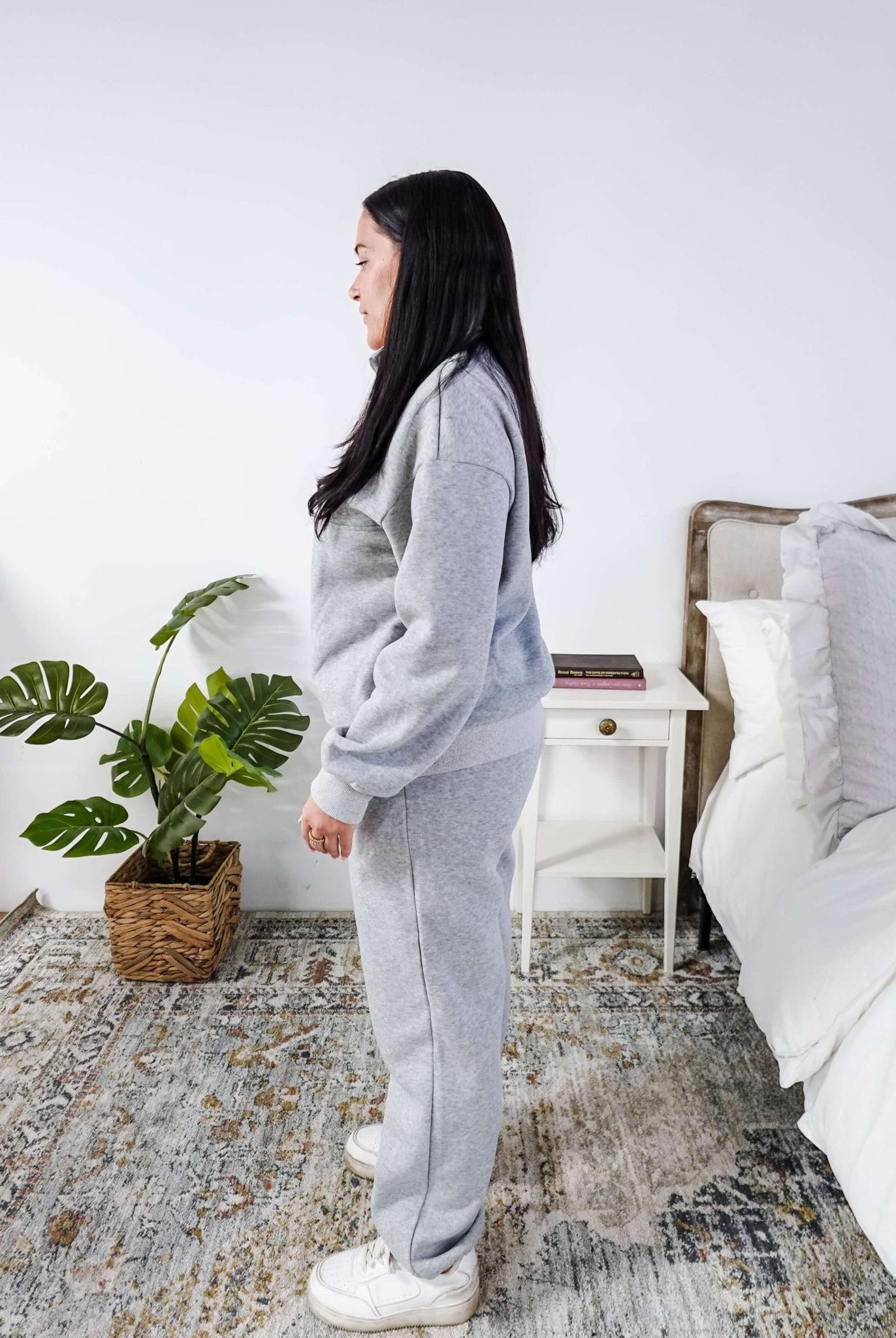Woman wearing a grey sweatsuit standing in a bedroom with a plant and bed in the background, Scarlett Ellie Half-Zip Sweatsuit Set | Cloud Nine Pajamas