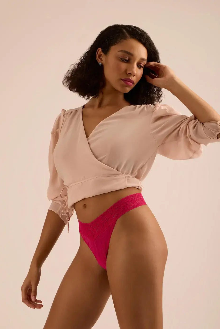 Model showcasing the Hanky Panky Original Rise Thong in pink, featuring signature lace design, wearing a stylish wrap top.