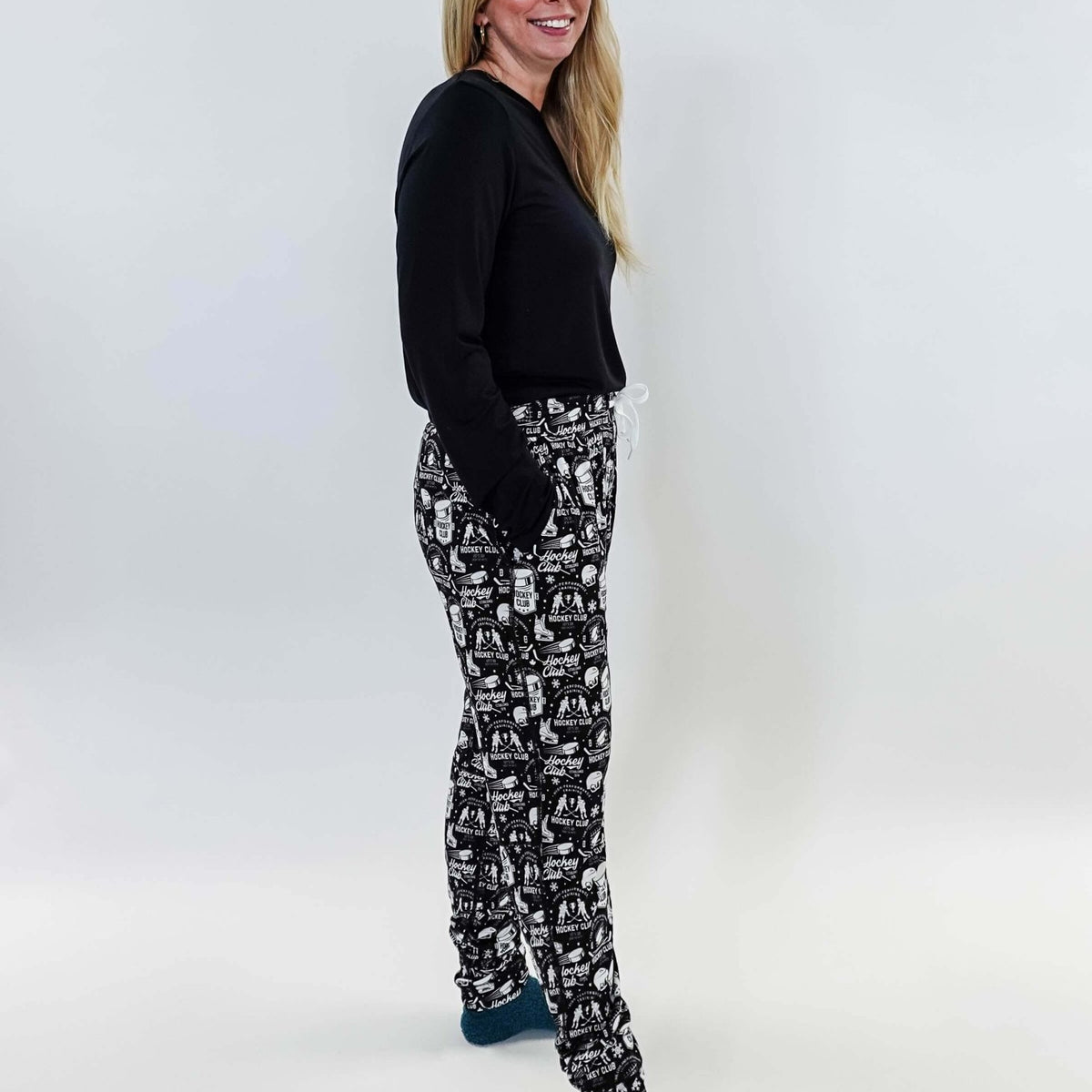Female model wearing He Scores Hockey Print Unisex Bamboo Jogger with a black long-sleeve top and blue socks.