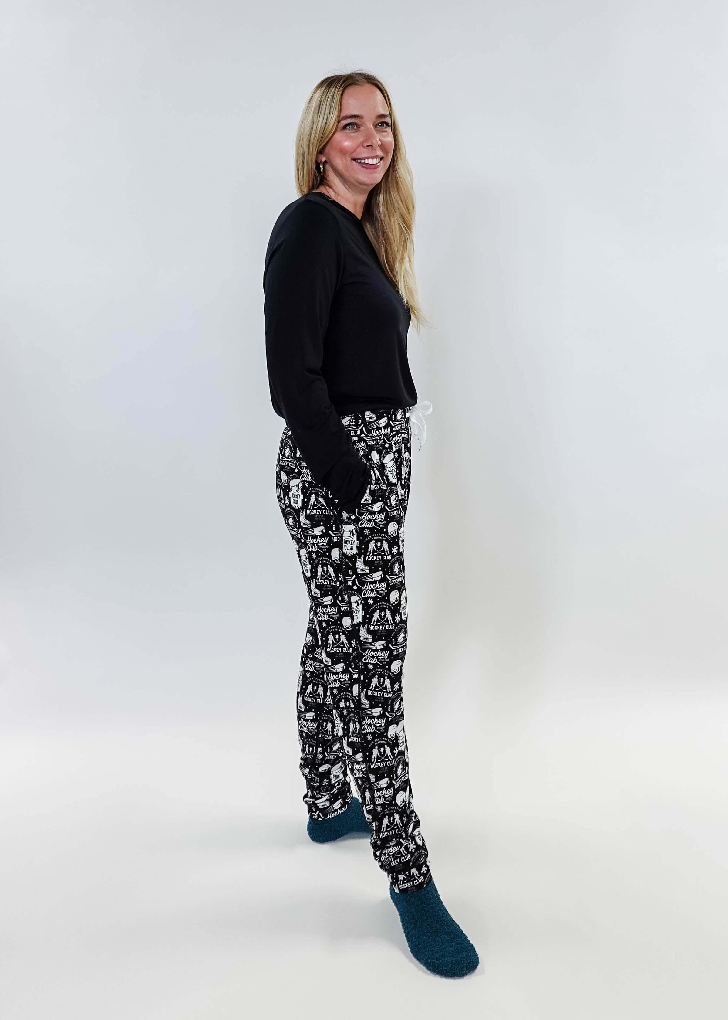 Female model wearing He Scores Hockey Print Unisex Bamboo Jogger with a black long-sleeve top and blue socks.