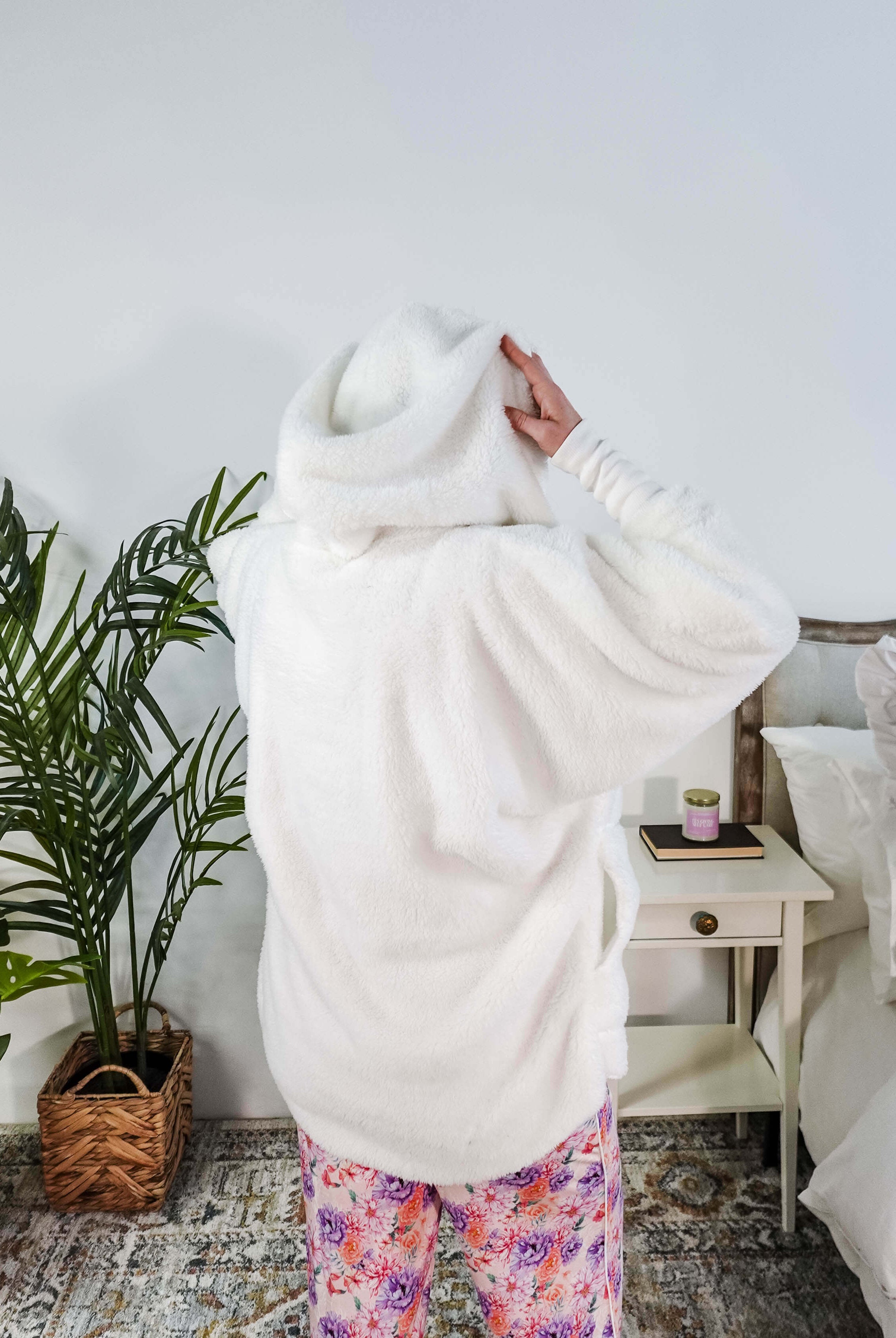 Essential Hooded Fluffy Cozy Cardigan with Pockets worn by a woman with floral pajamas in a cozy bedroom setting.