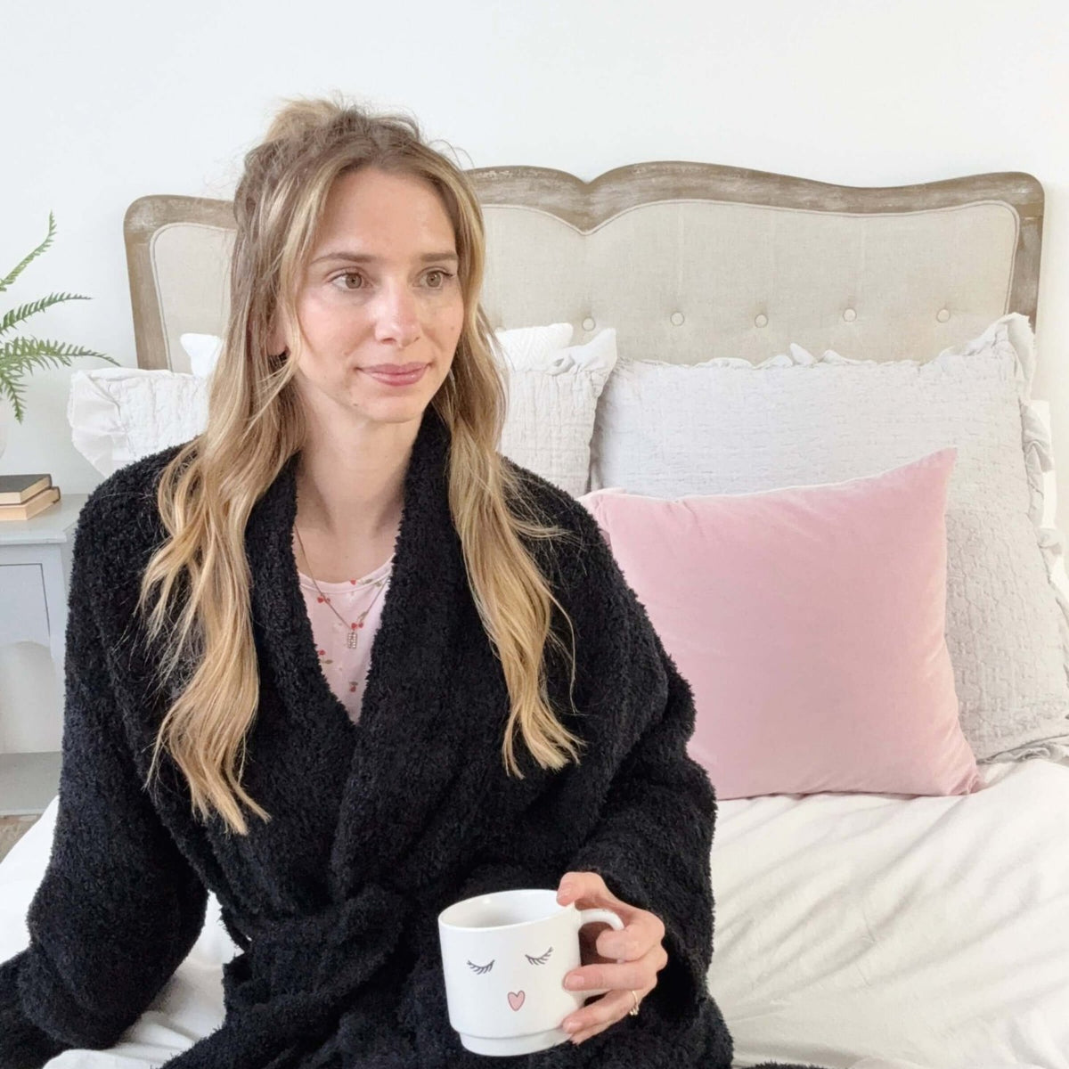 Black Chenille Cloud Spa Robe | Cozy Plush Lounge Woman in a black robe holding a mug on a bed with pink and gray pillows.