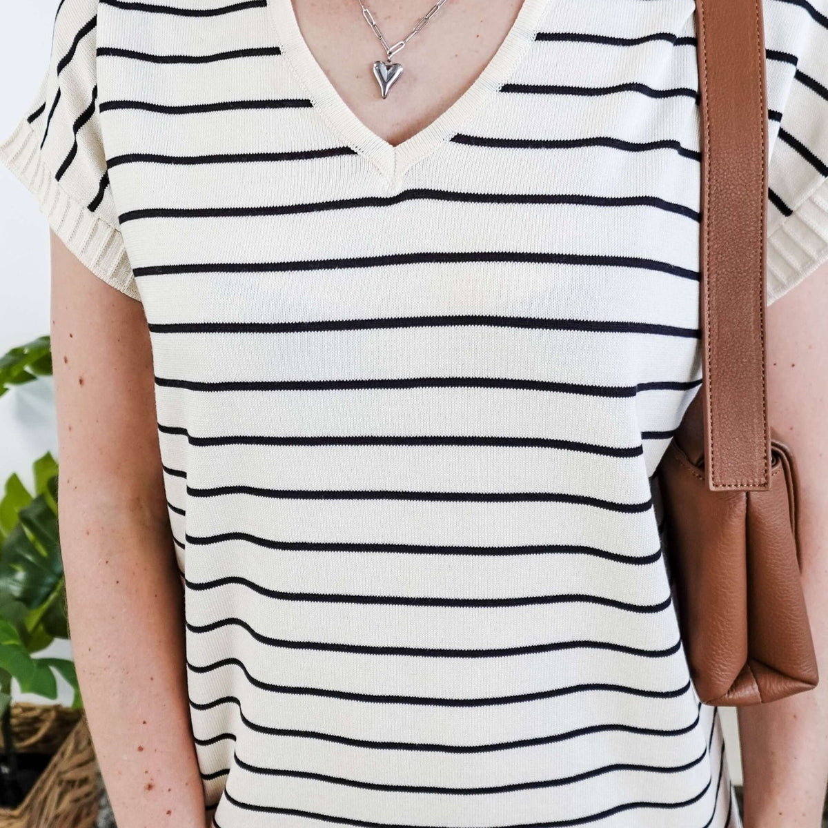 Person wearing a black and white striped dress with a brown bag.