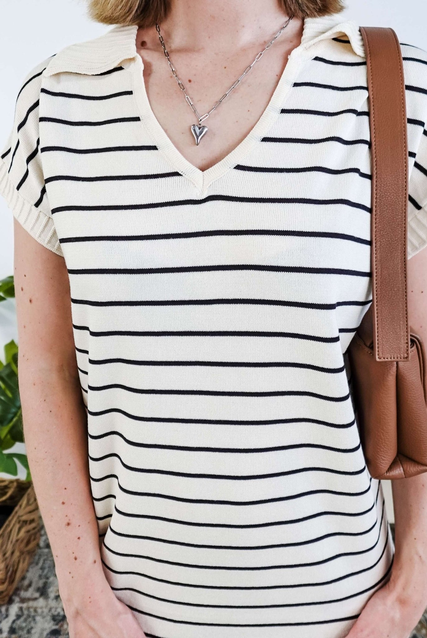 Person wearing a black and white striped dress with a brown bag.