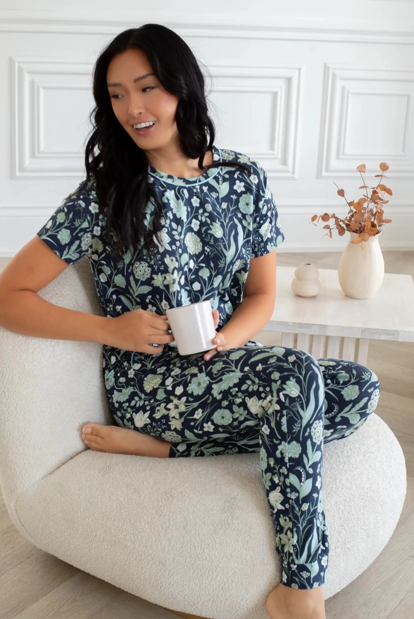 Model wearing Latte Love Floral Print Cotton-Modal Relaxed Set Drop Shoulder Tee & Jogger Set while holding a cup.