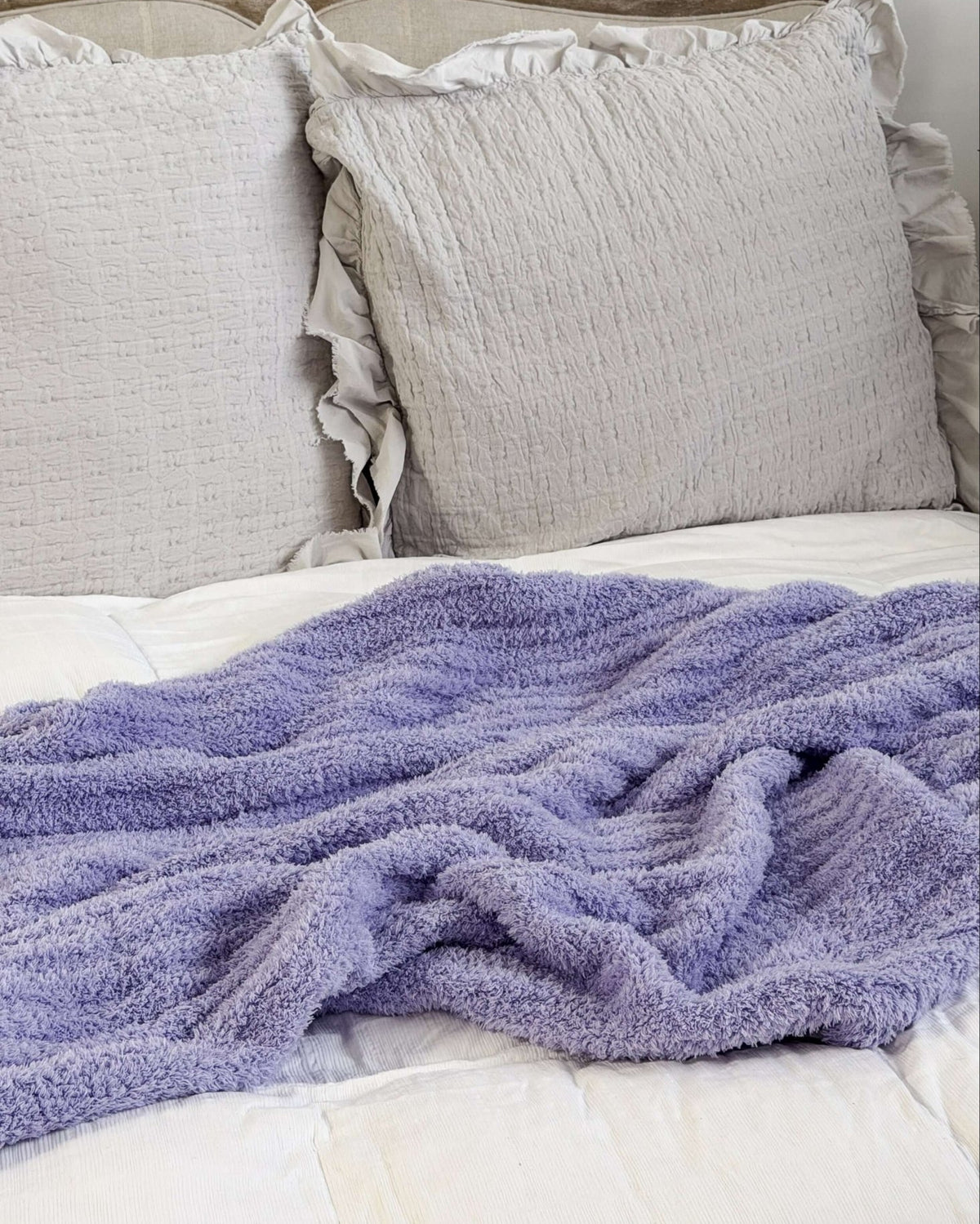 Lavender plush blanket Lounge by Jan Marie Bed with gray pillows and a purple blanket on a white background