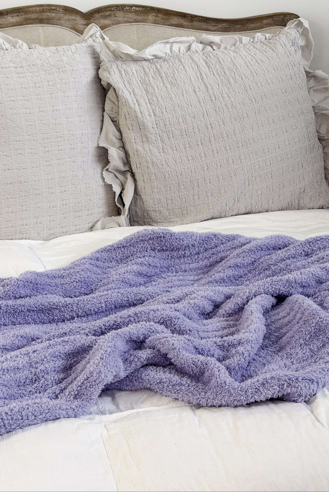 Lavender plush blanket Lounge by Jan Marie Bed with gray pillows and a purple blanket on a white background