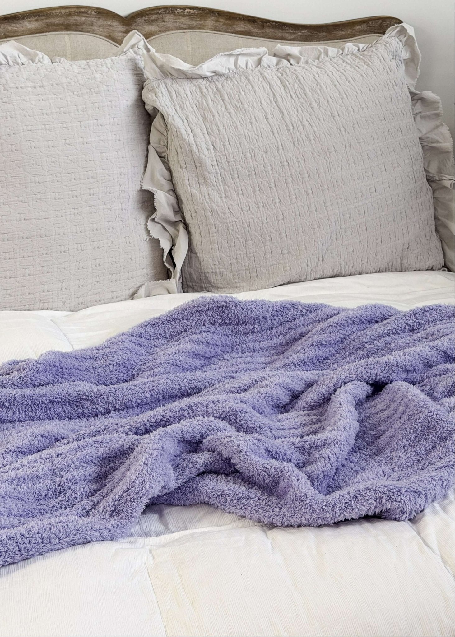 Lavender plush blanket Lounge by Jan Marie Bed with gray pillows and a purple blanket on a white background