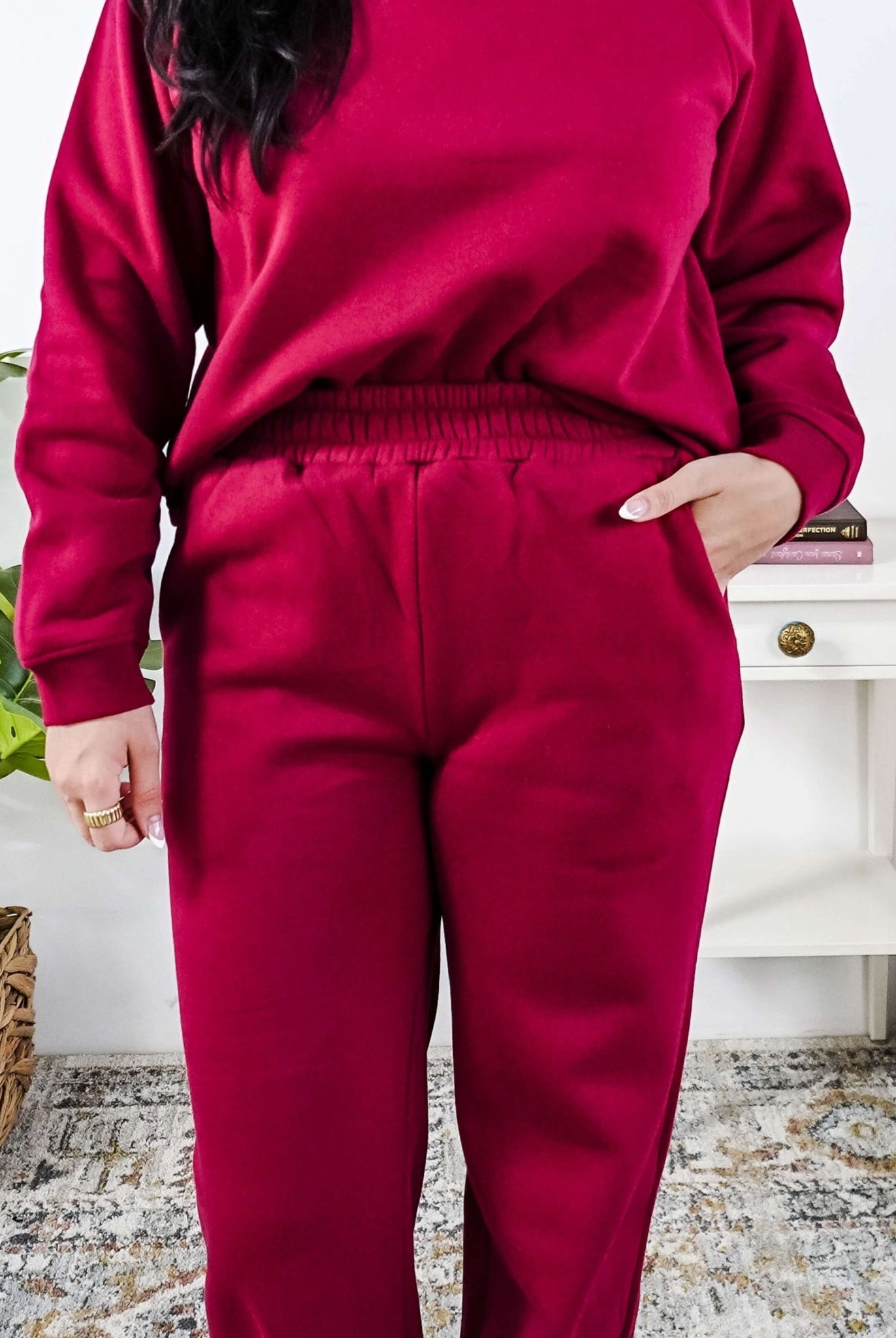 Woman wearing a red lounge outfit standing in a bedroom.