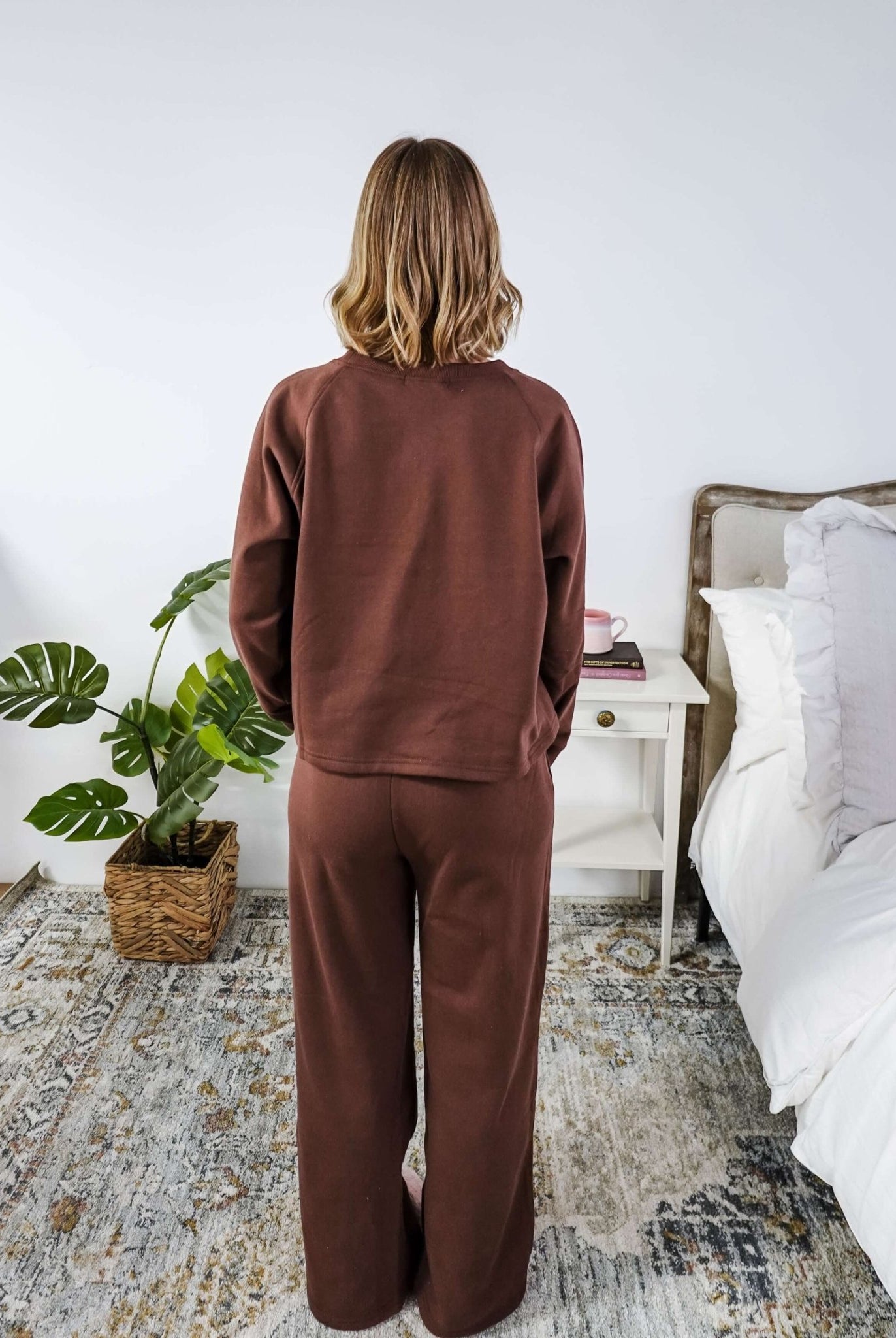 Person wearing a brown sweatsuit in a bedroom setting