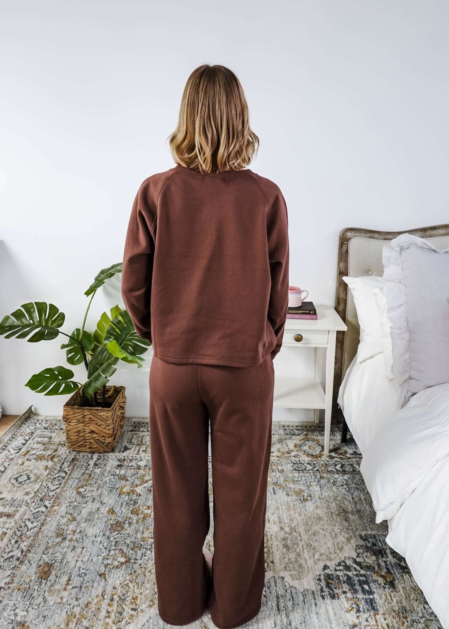 Person wearing a brown sweatsuit in a bedroom setting