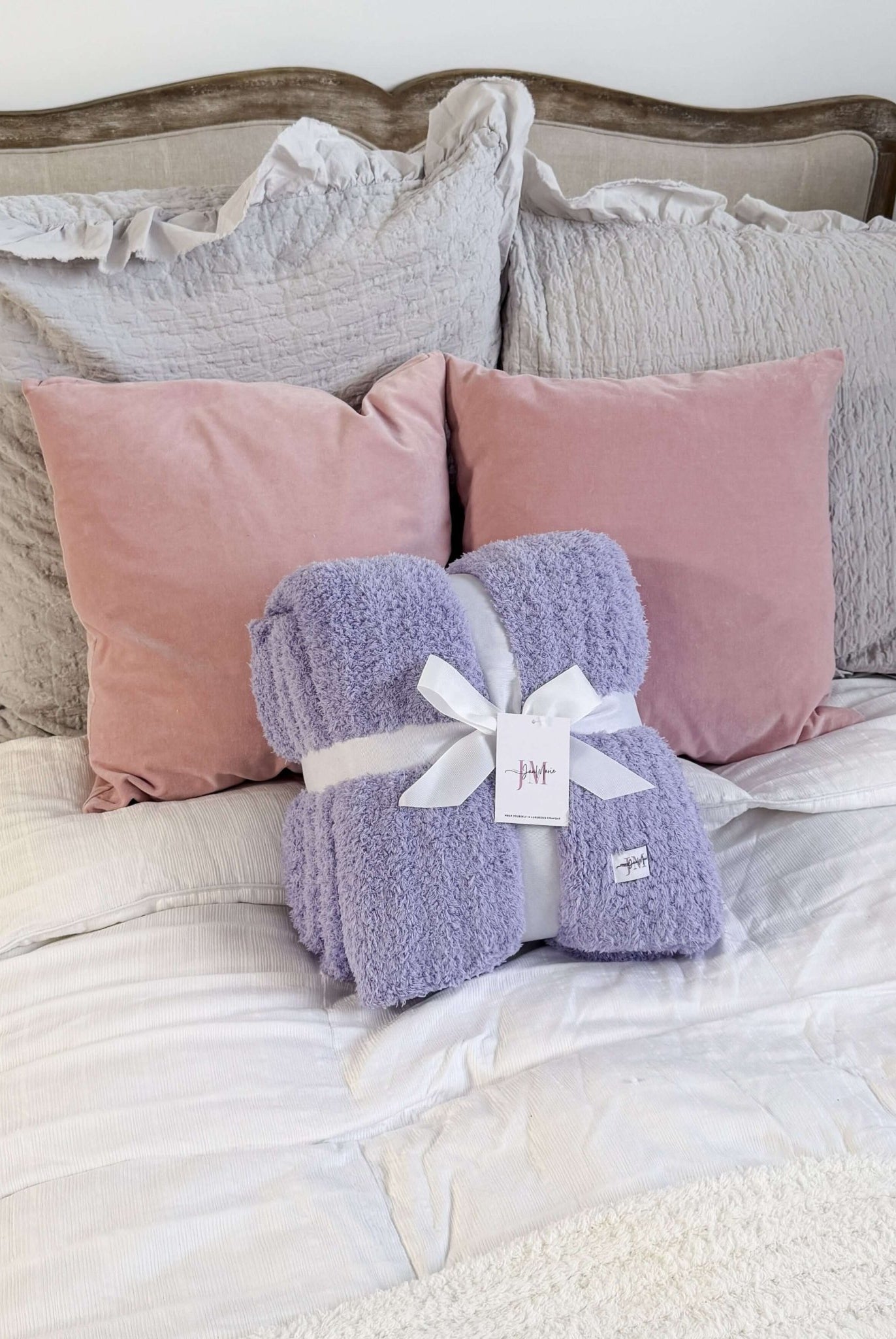 Lavender Purple Plush Cozy Cabin Blanket by Jan Marie - Purple blanket with a white tag on a bed with pink and gray pillows.