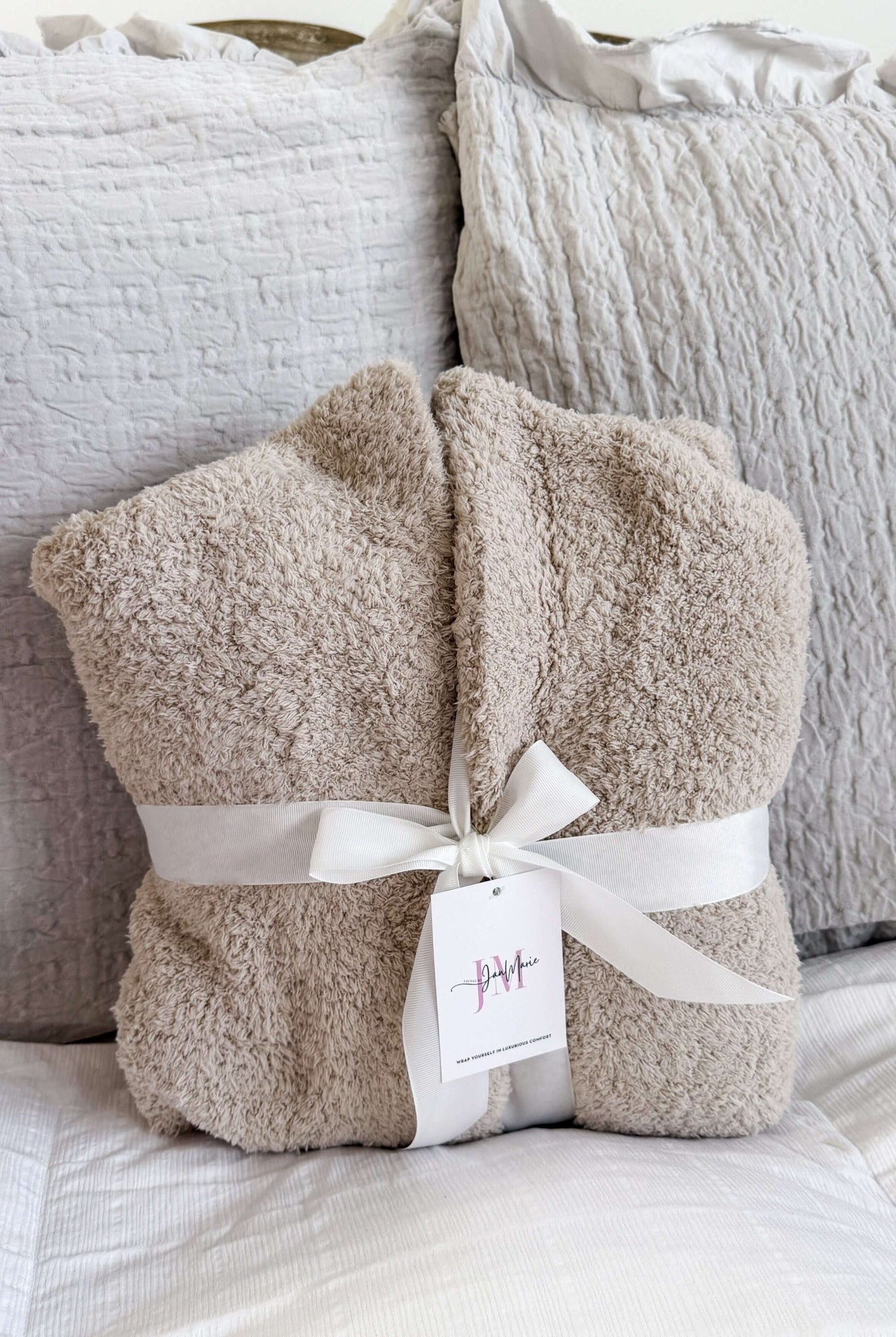 Sand Beige Chenille Cloud Spa Robe – Plush Stretch Robe with Pockets - showing robe folded in a square on the bed and wrapped in a fabric white wide ribbon, which is how it's sold making a great gift presentation