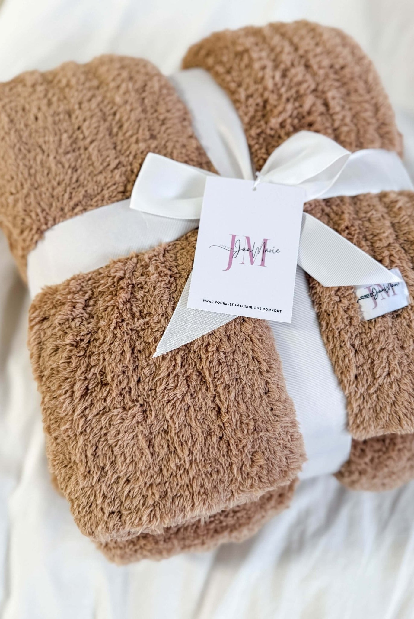 Mocha Brown Cozy Cabin Blanket with a white ribbon and tag on a light background