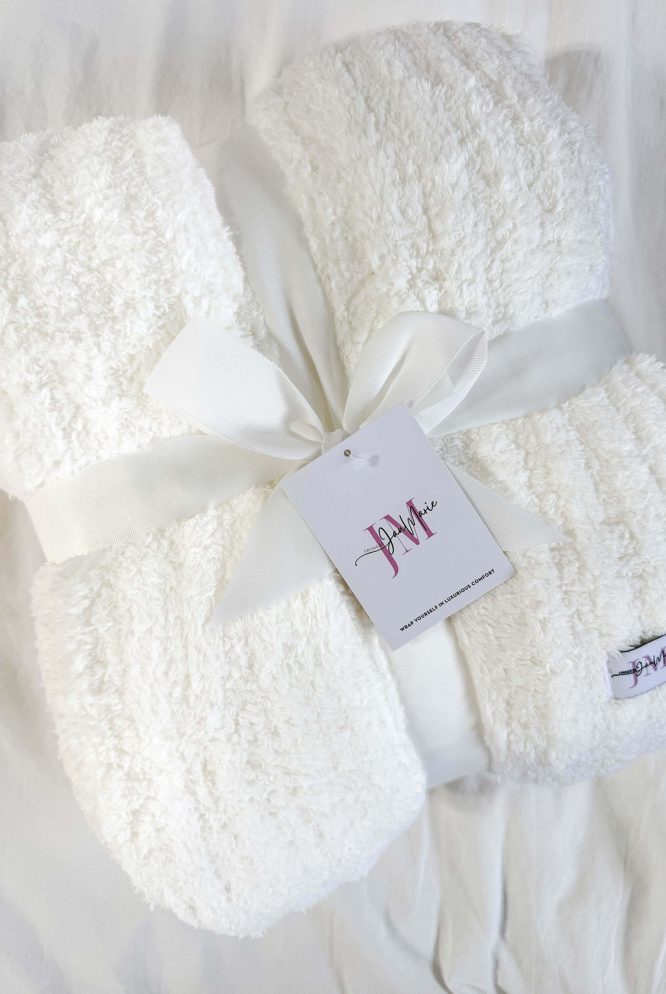 ivory white plush blanket on white background wrapped with a ribbon
