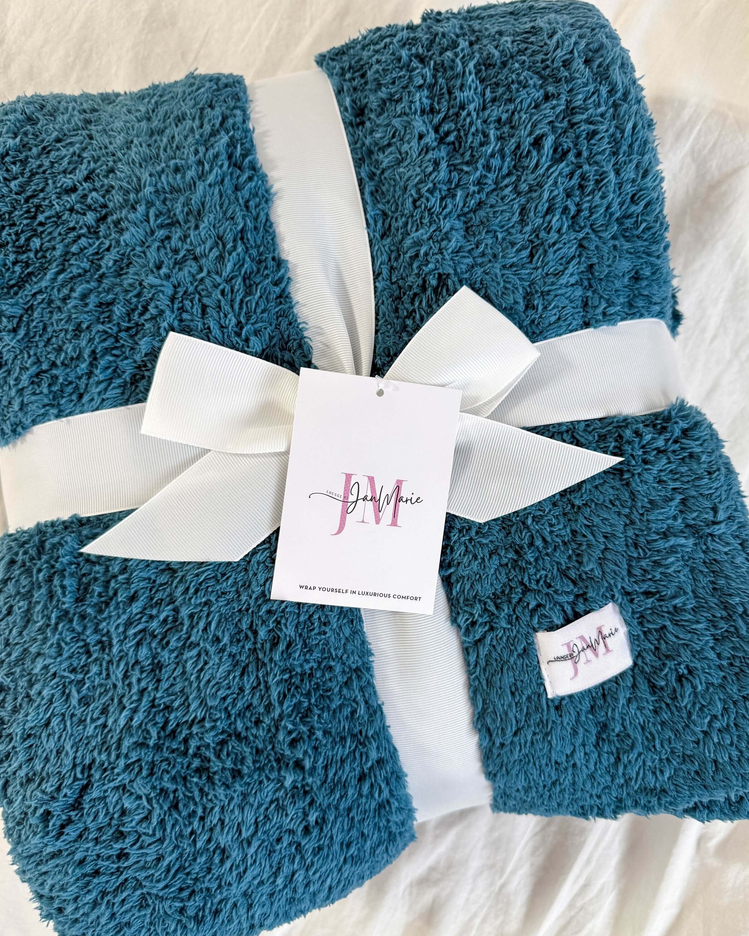 teal blue plush blanket rapped in ribbon on white background
