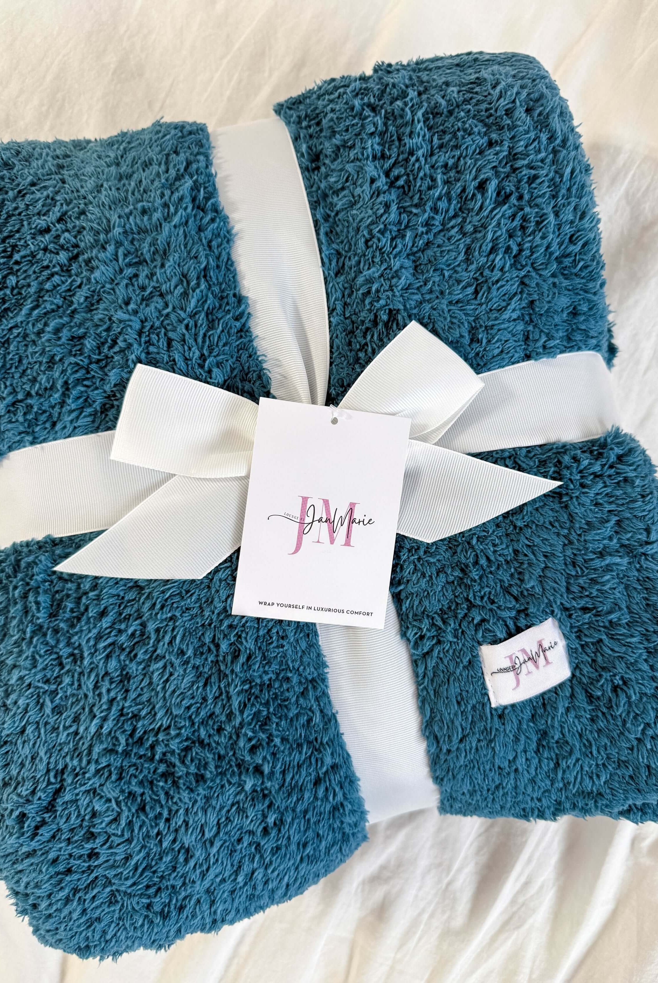 teal blue plush blanket rapped in ribbon on white background
