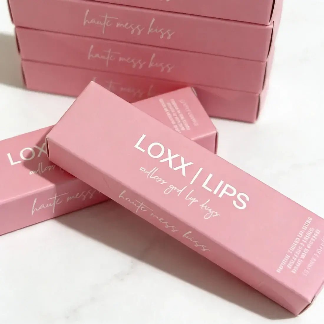 LOXX LIPS Peptide Lip Gloss Haute Mess Kiss Pink Tint packaging displayed on a marble surface.
