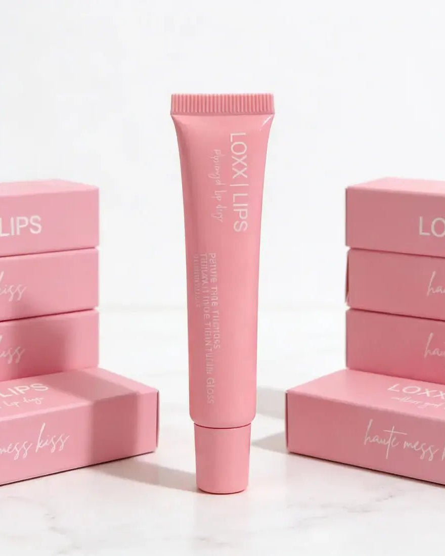 LOXX LIPS Peptide Lip Gloss Haute Mess Kiss Pink Tint packaging displayed, featuring a tube in front of pink boxes.