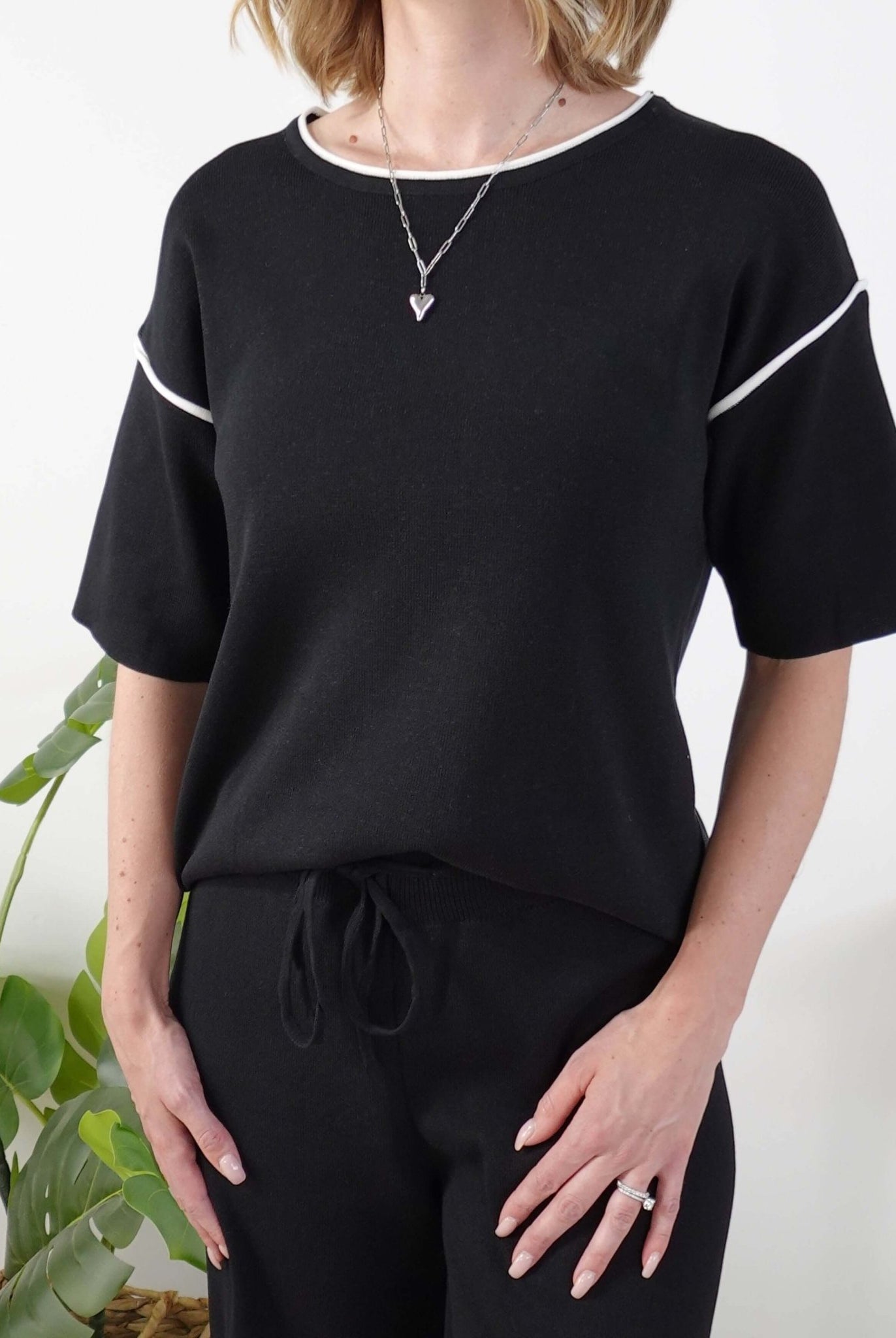 Person wearing a black outfit with white trim on a plain background