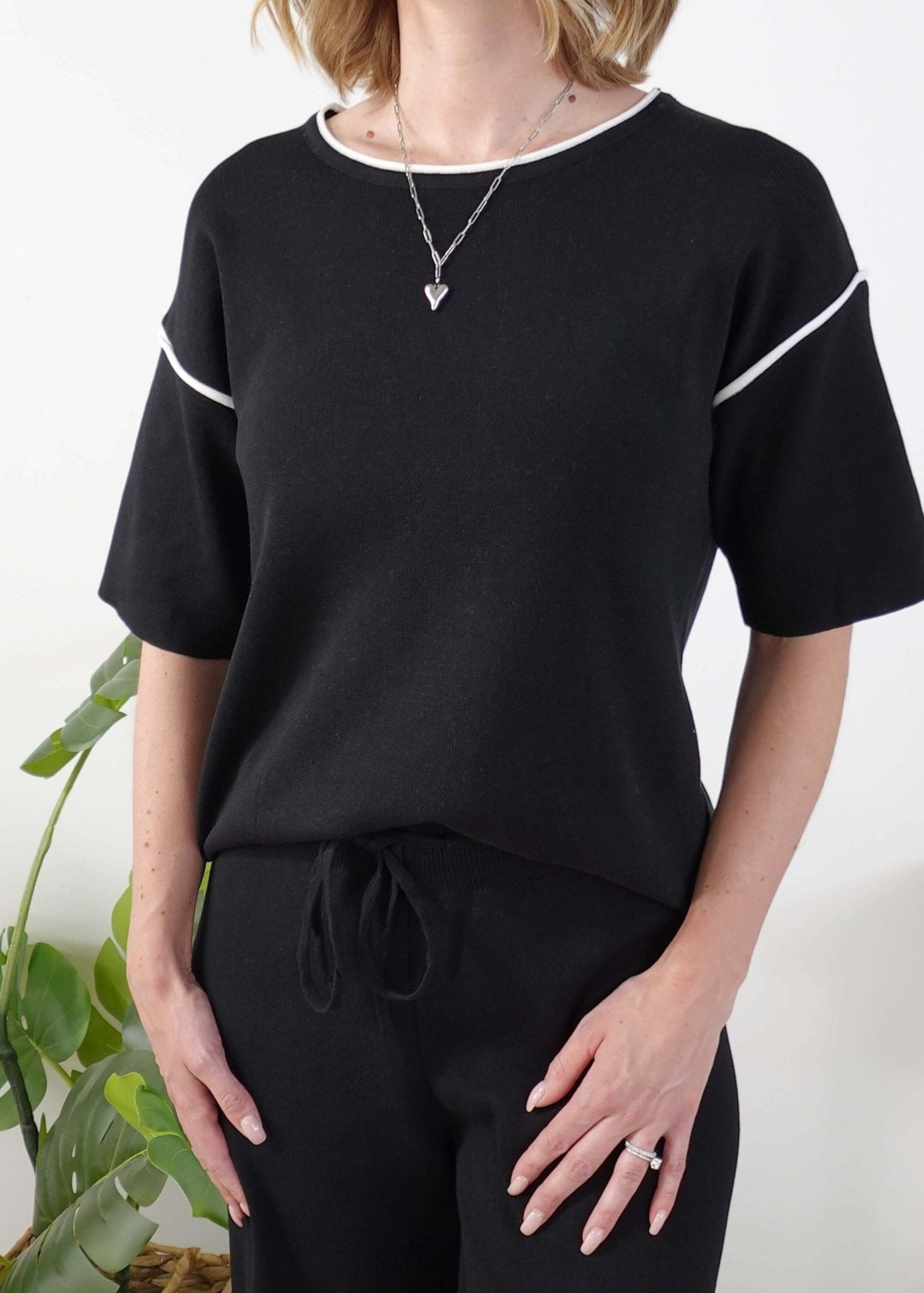 Person wearing a black outfit with white trim on a plain background