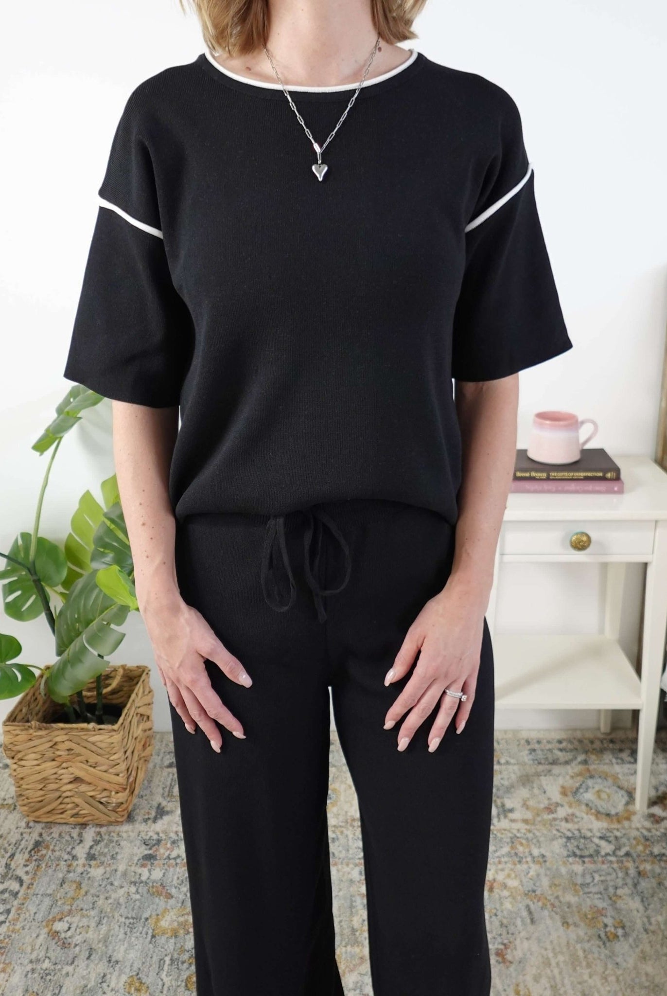 Person wearing a black outfit with white trim in a home setting