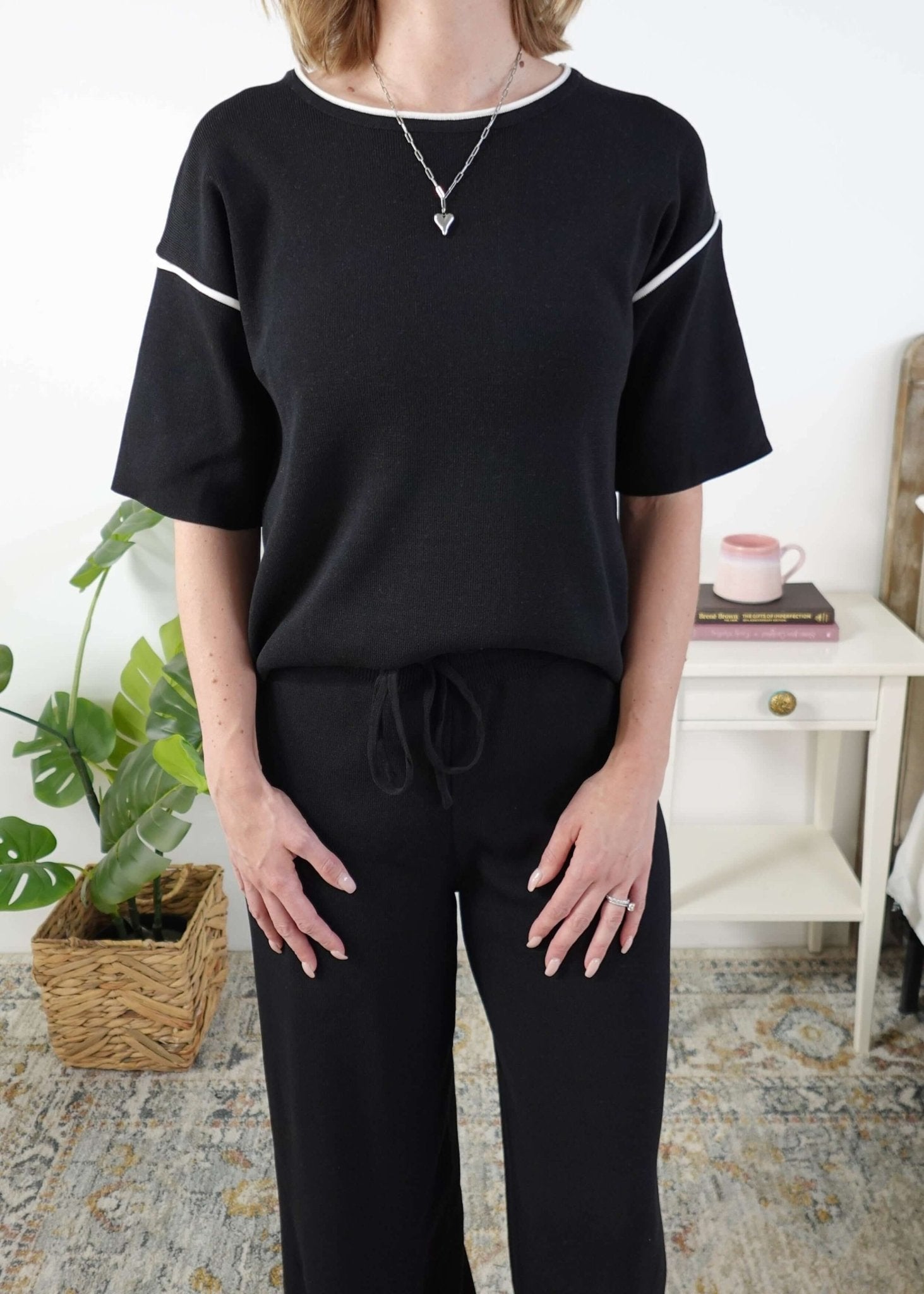 Person wearing a black outfit with white trim in a home setting