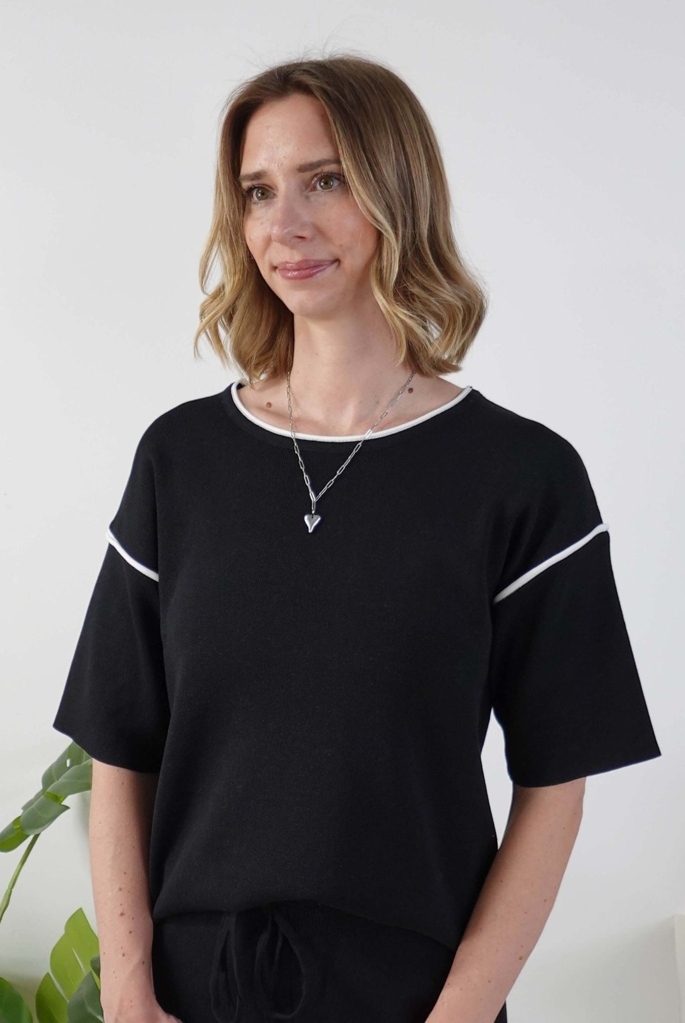 Woman wearing a black top with white trim against a white background