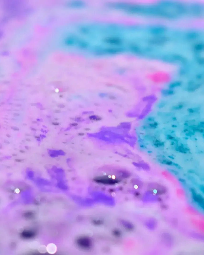 Colorful bath water showcasing the fizz and foam of Mermaid Bath Bomb Crumble in hues of purple and blue.
