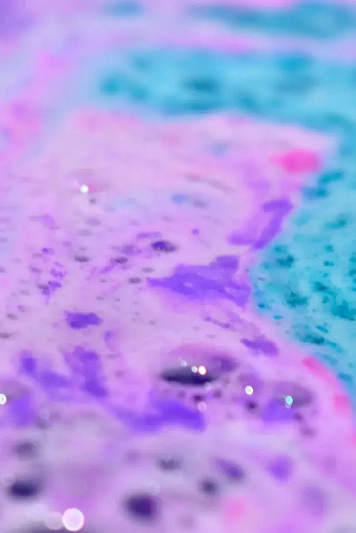 Colorful bath water showcasing the fizz and foam of Mermaid Bath Bomb Crumble in hues of purple and blue.