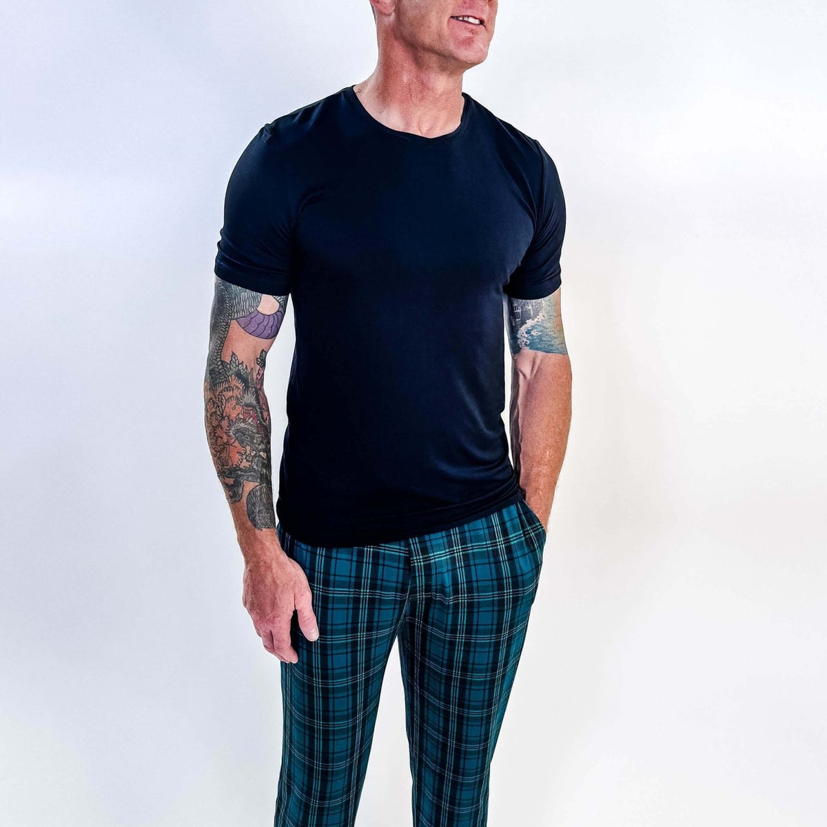 Man wearing Midnight Plaid Unisex Bamboo Joggers and a black shirt, showcasing comfort and style.